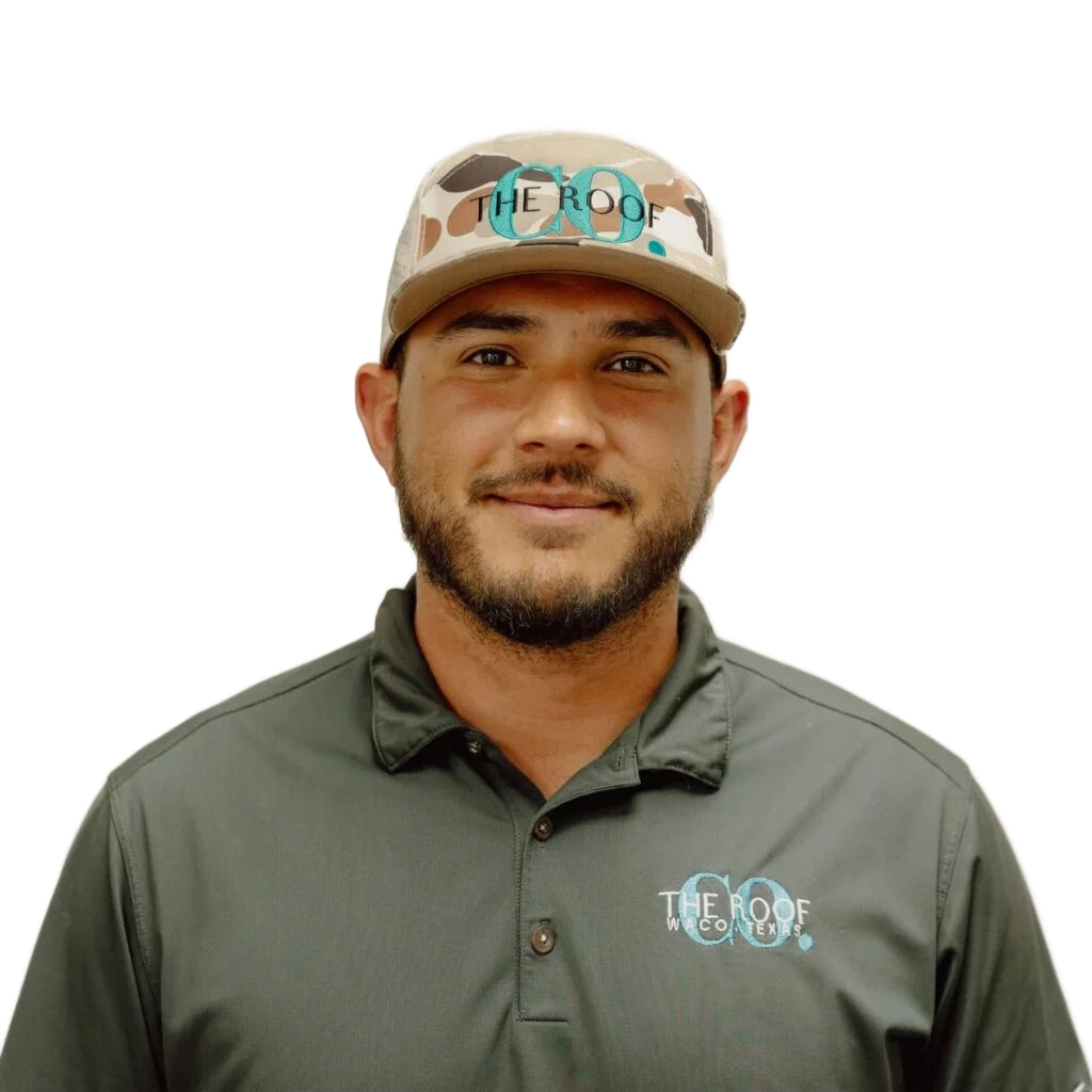 A man wearing a camouflage baseball cap and gray polo shirt, smiling at the camera. He has a beard and the logo 