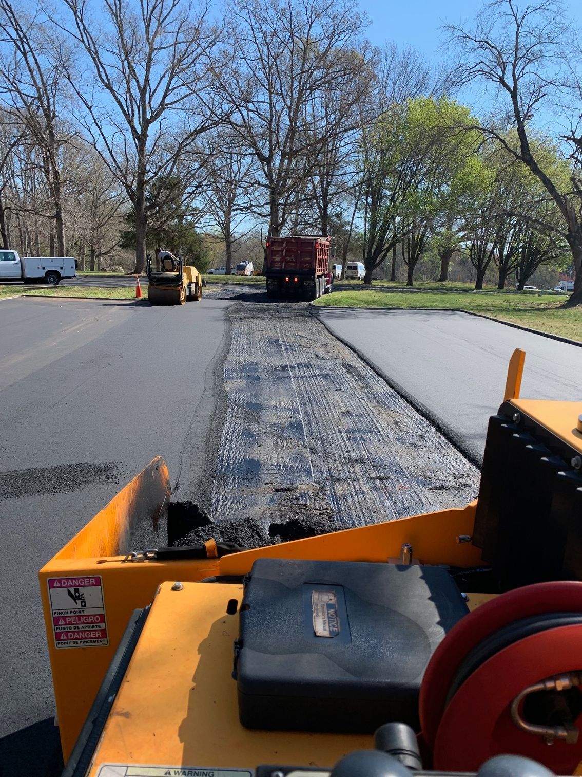 A yellow truck is driving down a road with trees in the background.