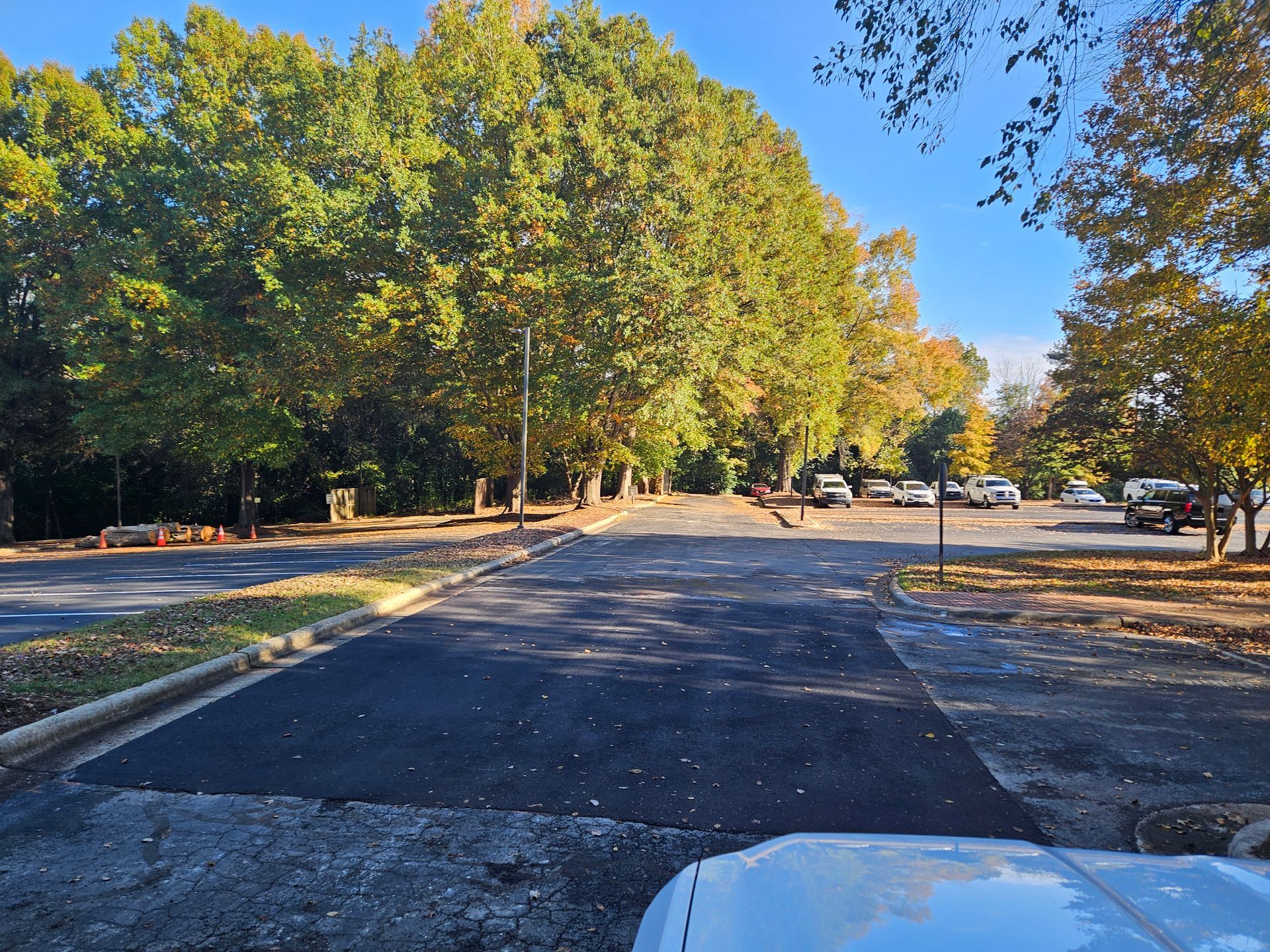 A white car is parked on the side of the road in a parking lot.