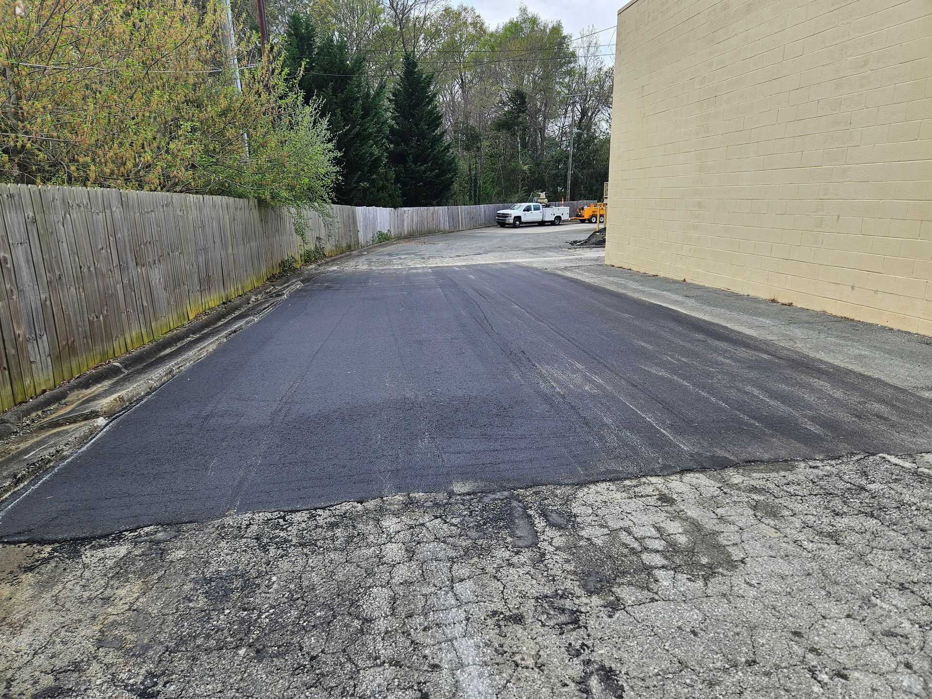 A brick building is behind a newly paved road.