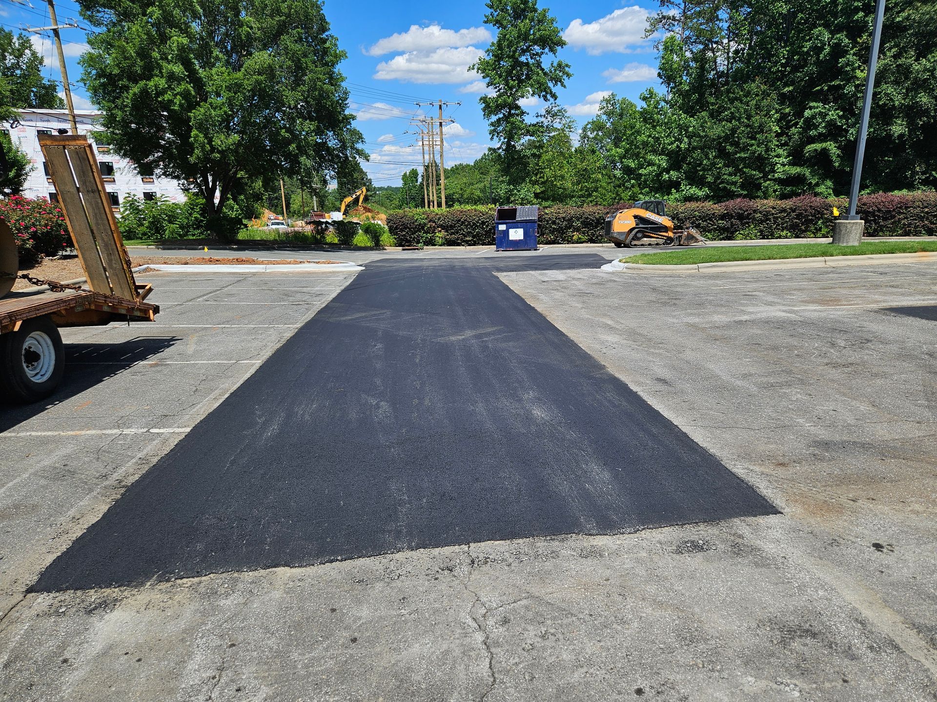 A large patch of asphalt is being installed in a parking lot.