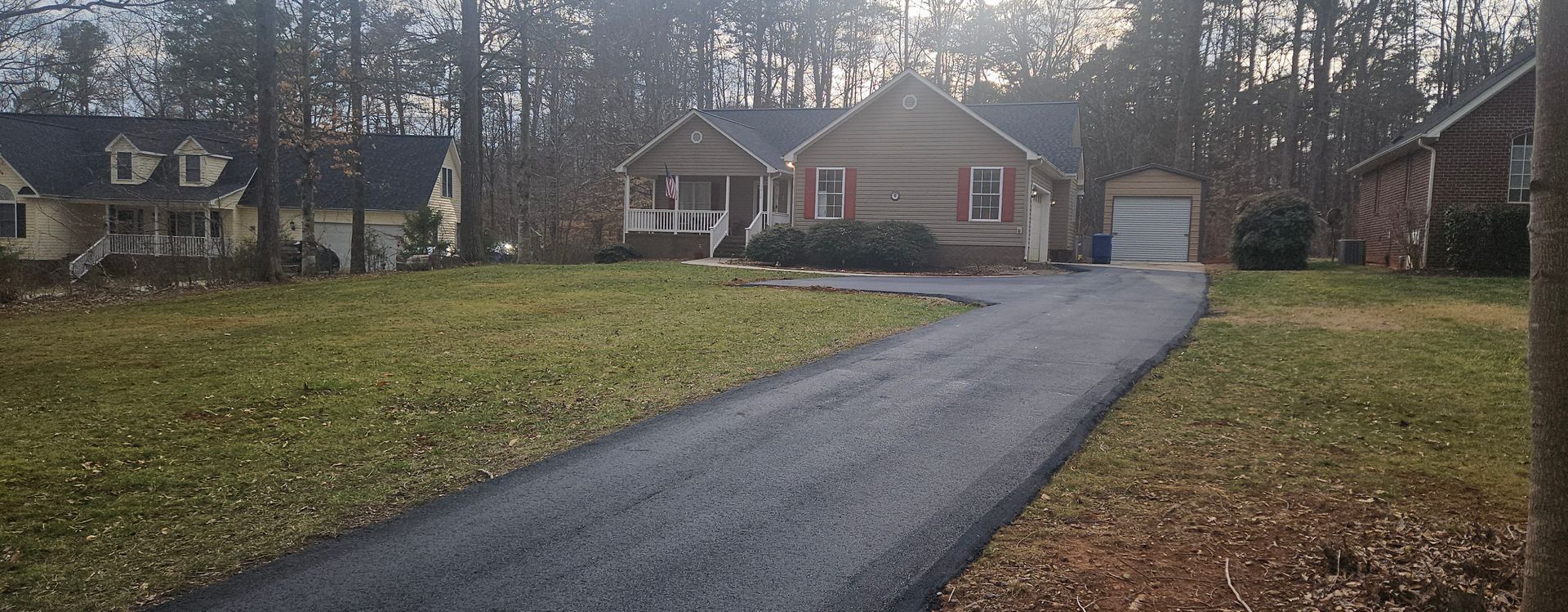 A driveway leading to a house in the woods.