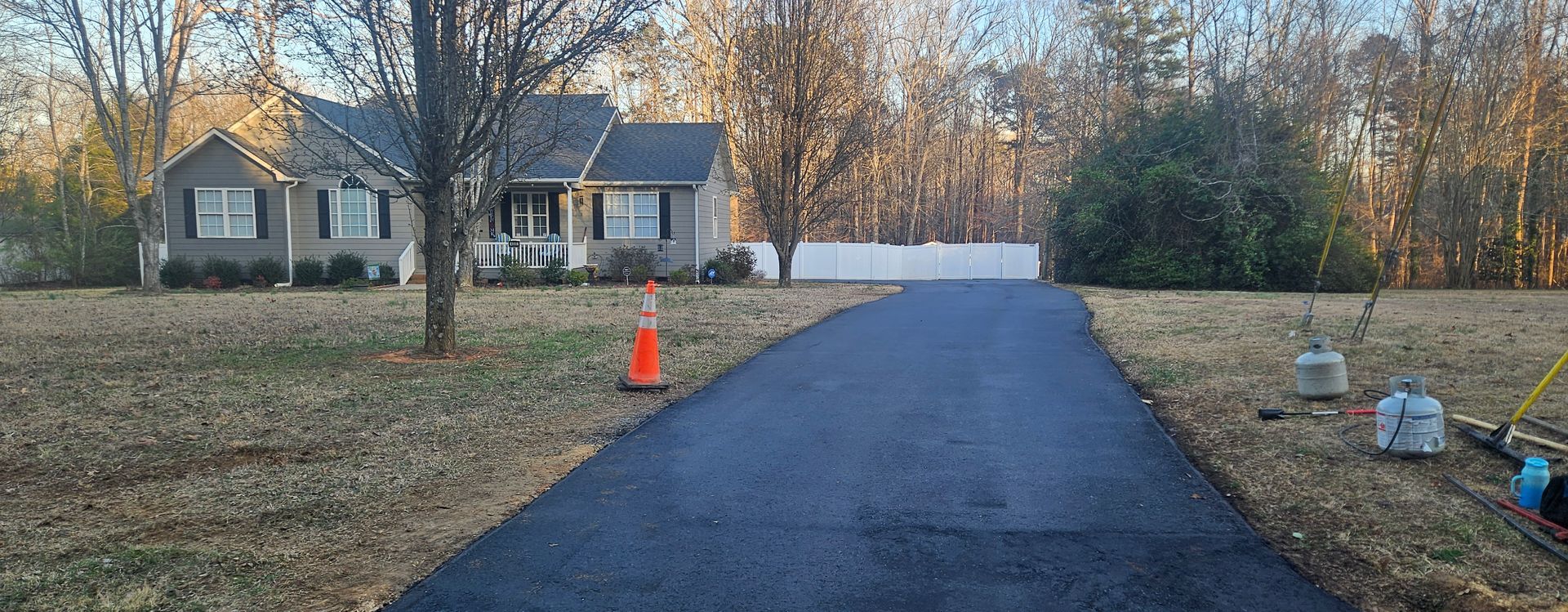 A driveway leading to a house in the middle of a field.