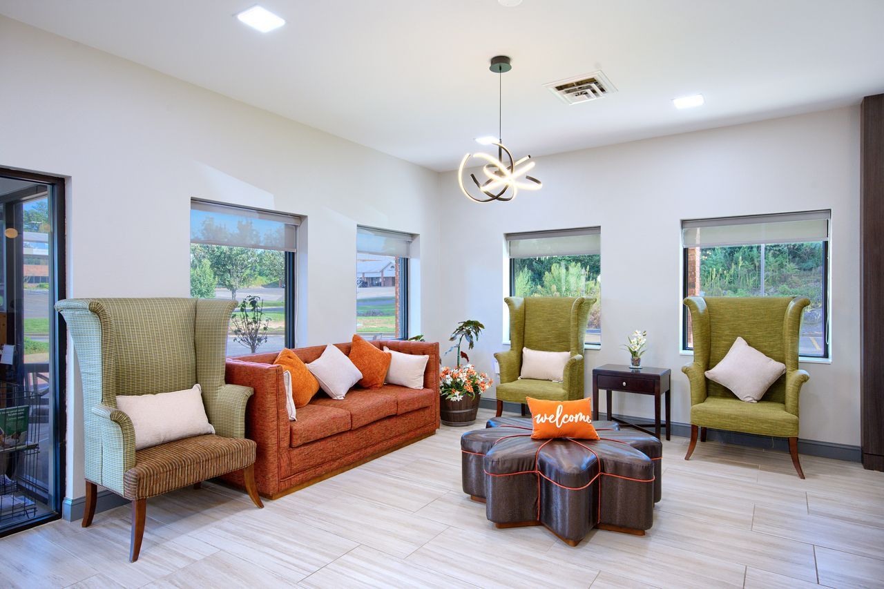 Swimming pool surrounded by a fence and trees on a sunny day. A small building sits near the pool.