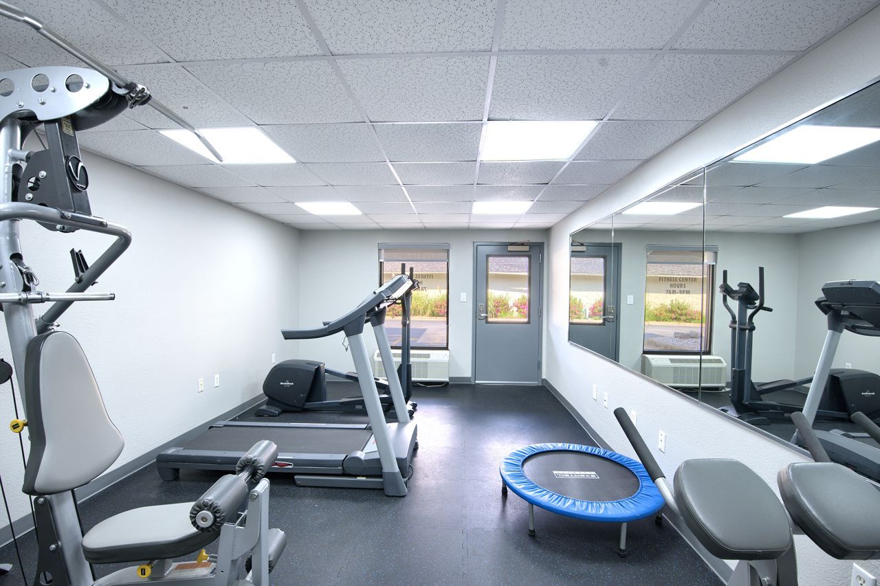 Gym with fitness equipment, including a treadmill, exercise machines, and a trampoline.