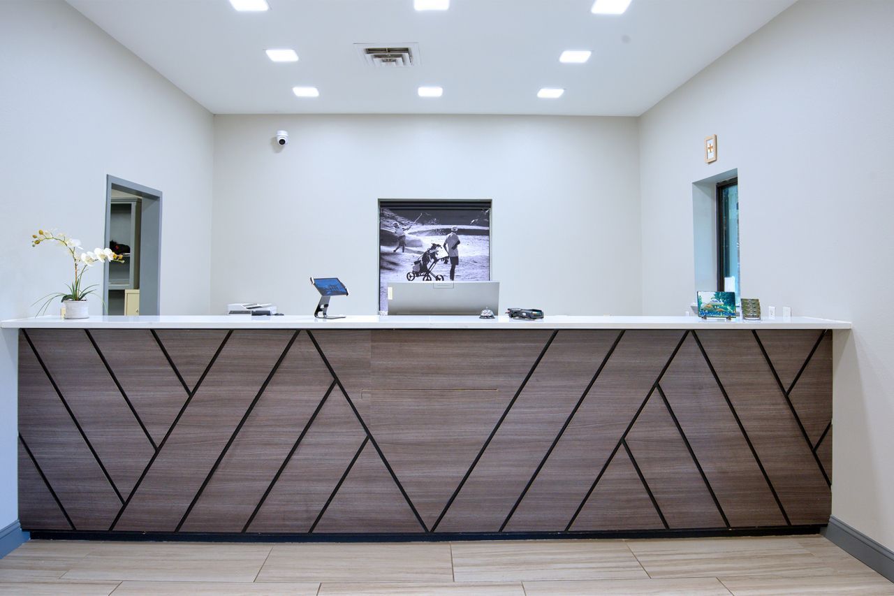 Spacious open room with seating areas, a dining table, and a buffet. Overhead lighting and windows provide light.