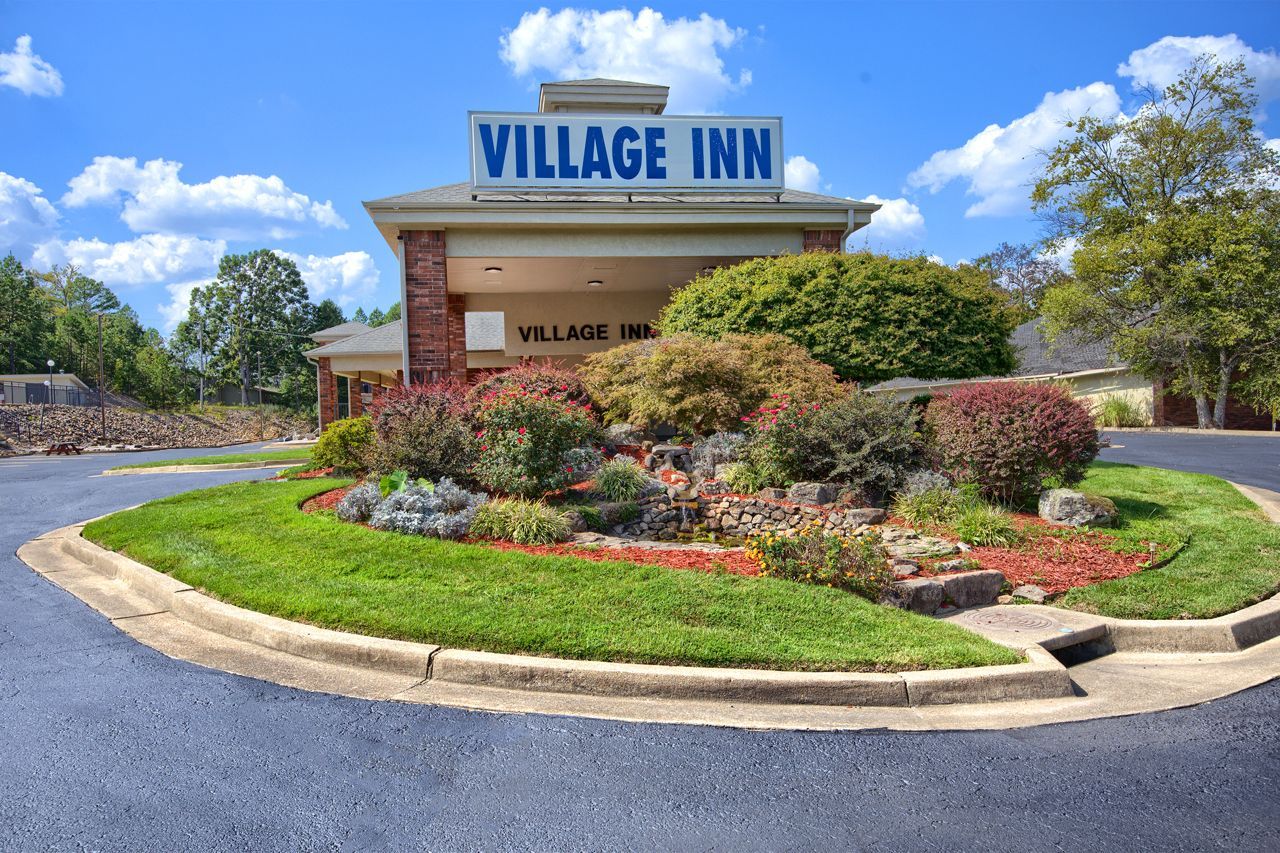 Village Inn hotel exterior with landscaping and blue sky.