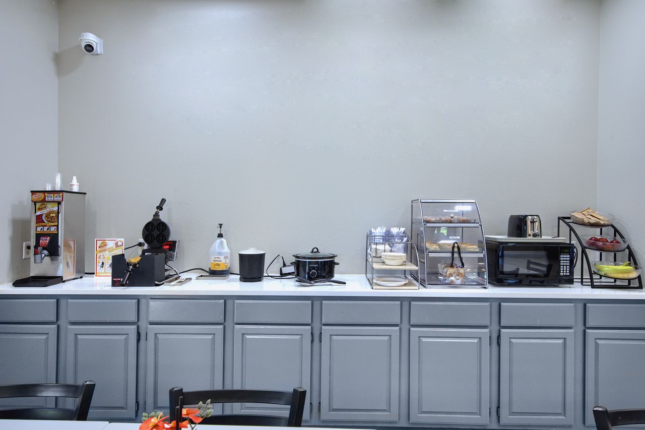 Breakfast buffet area with appliances on a counter and gray cabinets below.