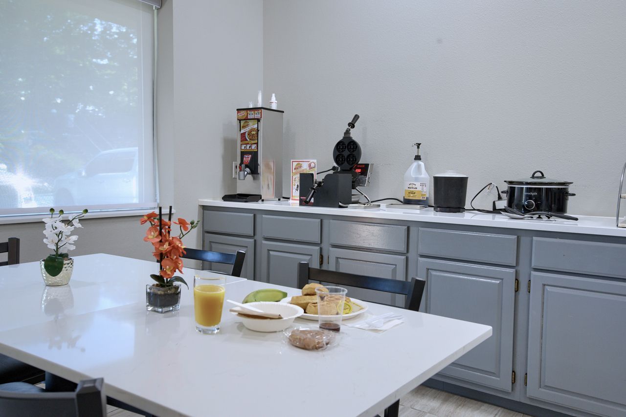 Breakfast area with table set, cabinets, and appliances like a coffee maker.