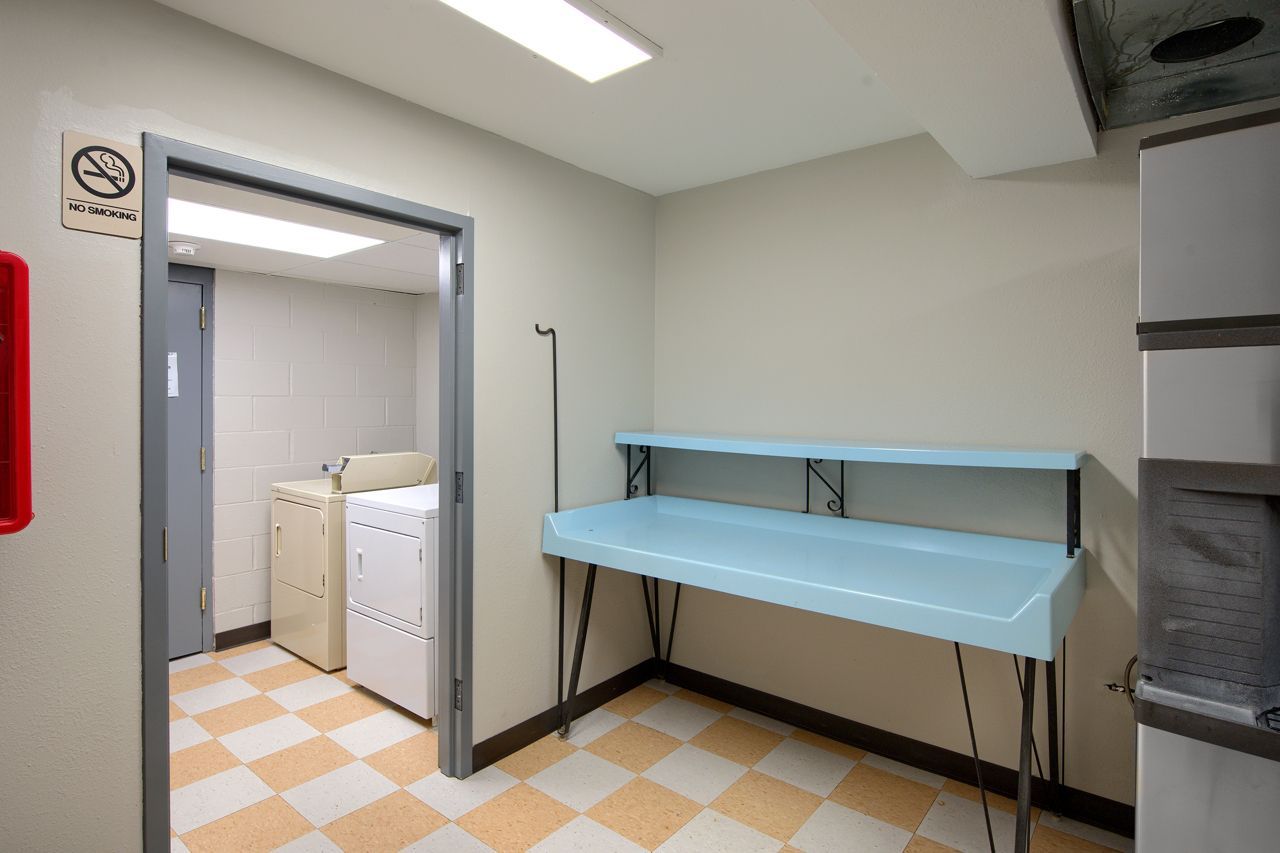 Laundry room with washing machine, blue counter, and checkerboard floor.