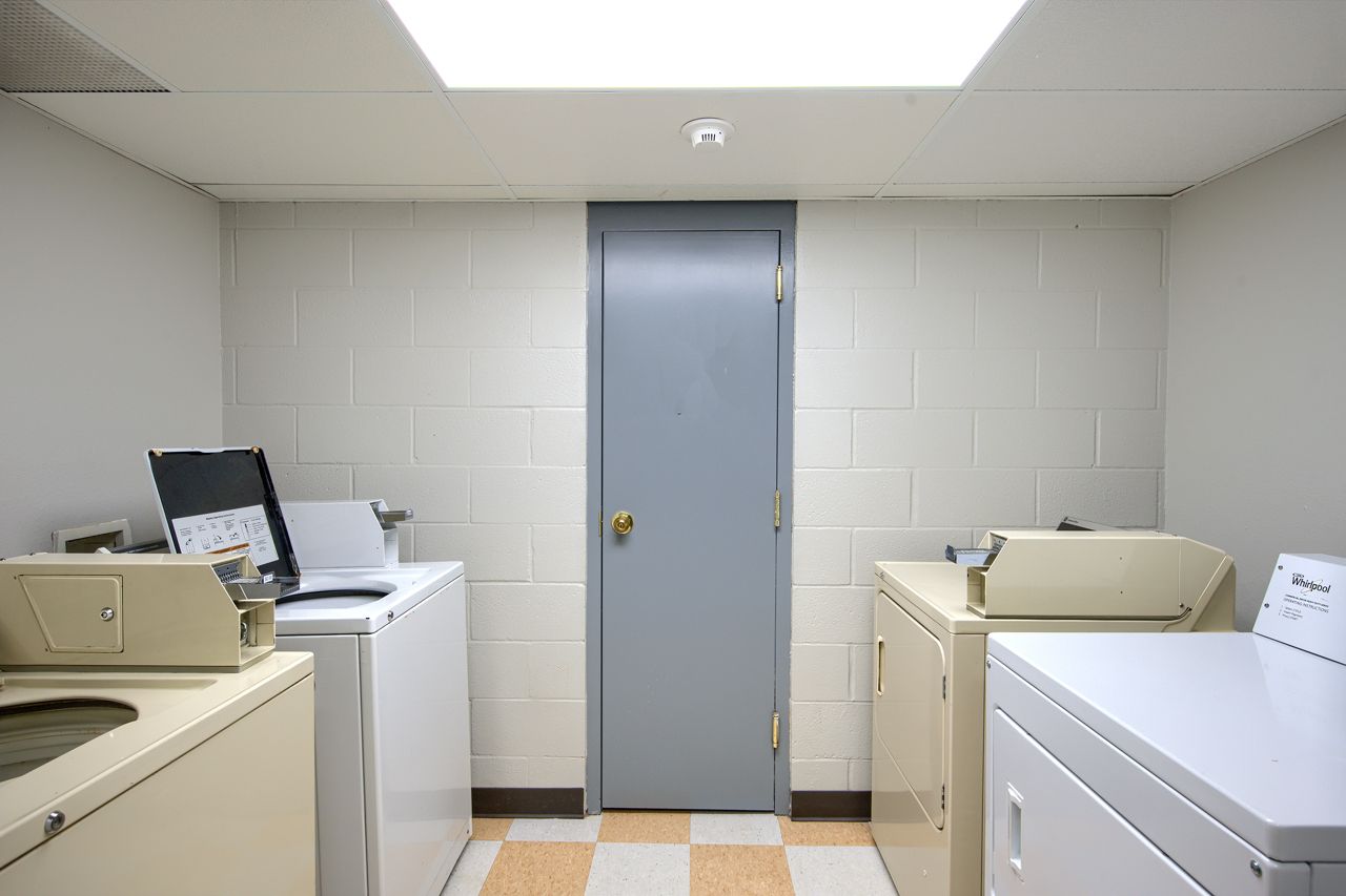 Laundry room with white appliances, white block walls, and a gray door.