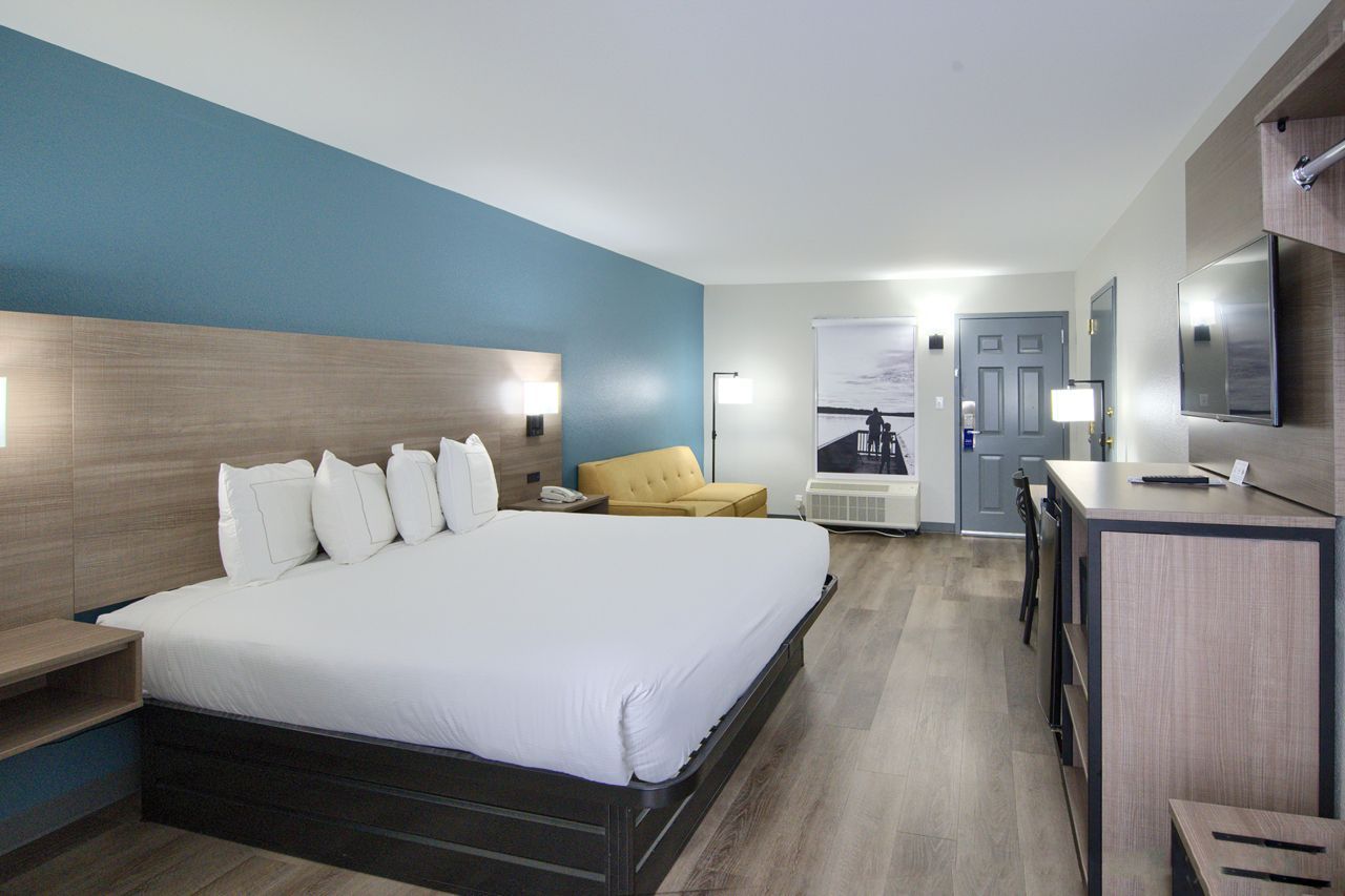 Hotel room with king bed, blue accent wall, neutral tones.