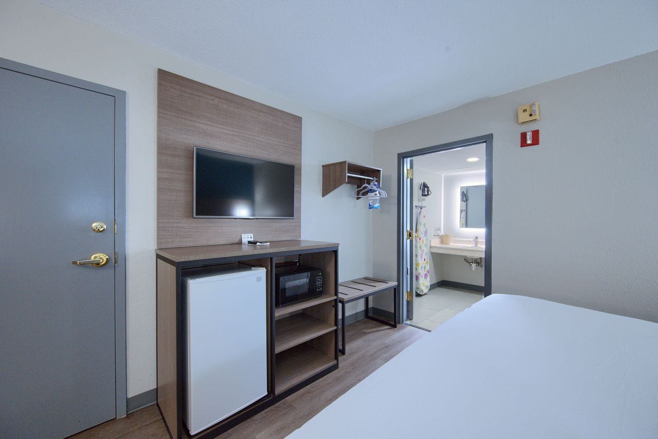 Hotel room with a TV, refrigerator, safe, and open bathroom.