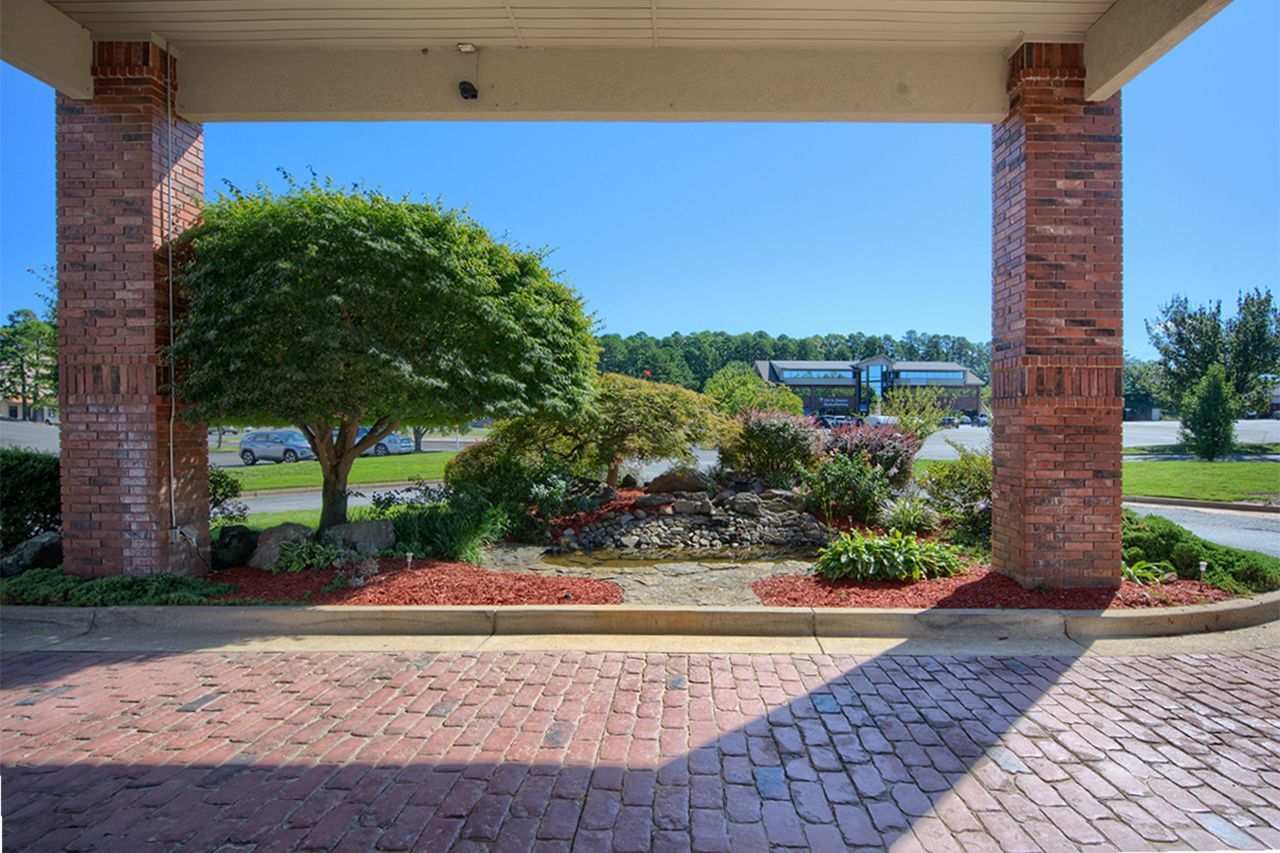 Pool area with blue water, white lounge chairs, and a small building under a clear blue sky.