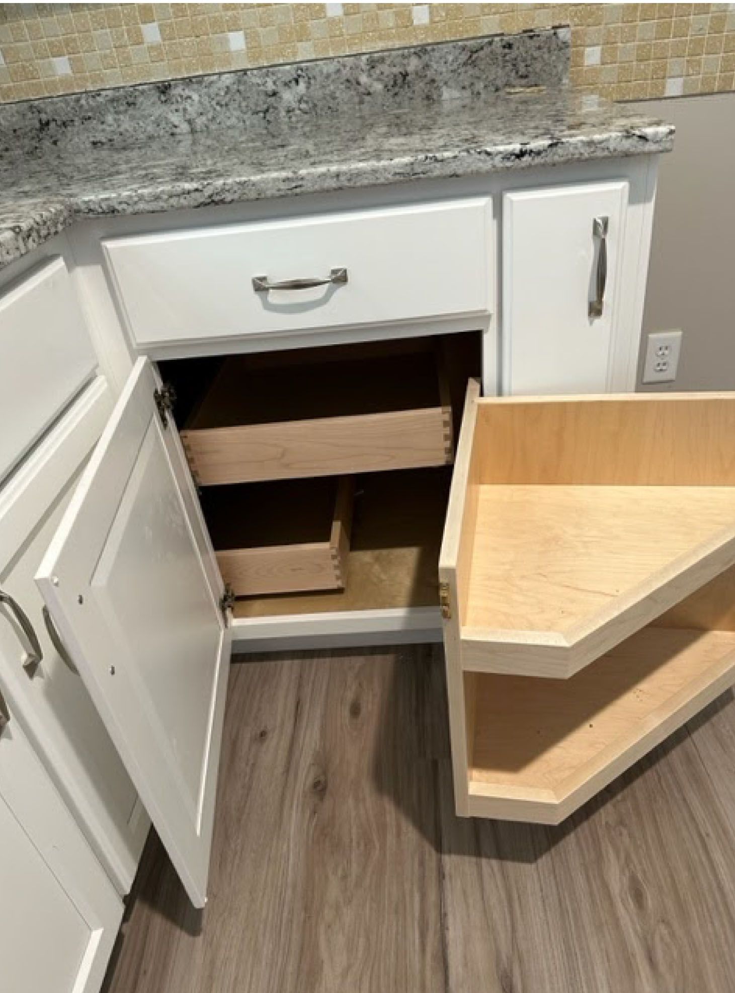 White kitchen cabinet open, revealing a pull-out spice rack and a rotating shelf.