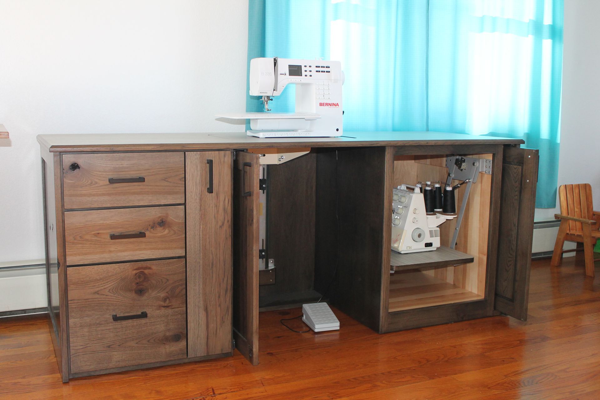 Sewing table with machine, drawers, and cabinet storage; white machine on a gray wood surface.
