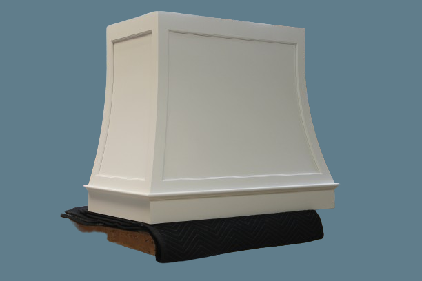 White kitchen range hood, curved design, resting on a black surface.