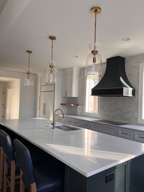 Modern kitchen with island, pendant lights, and black range hood.