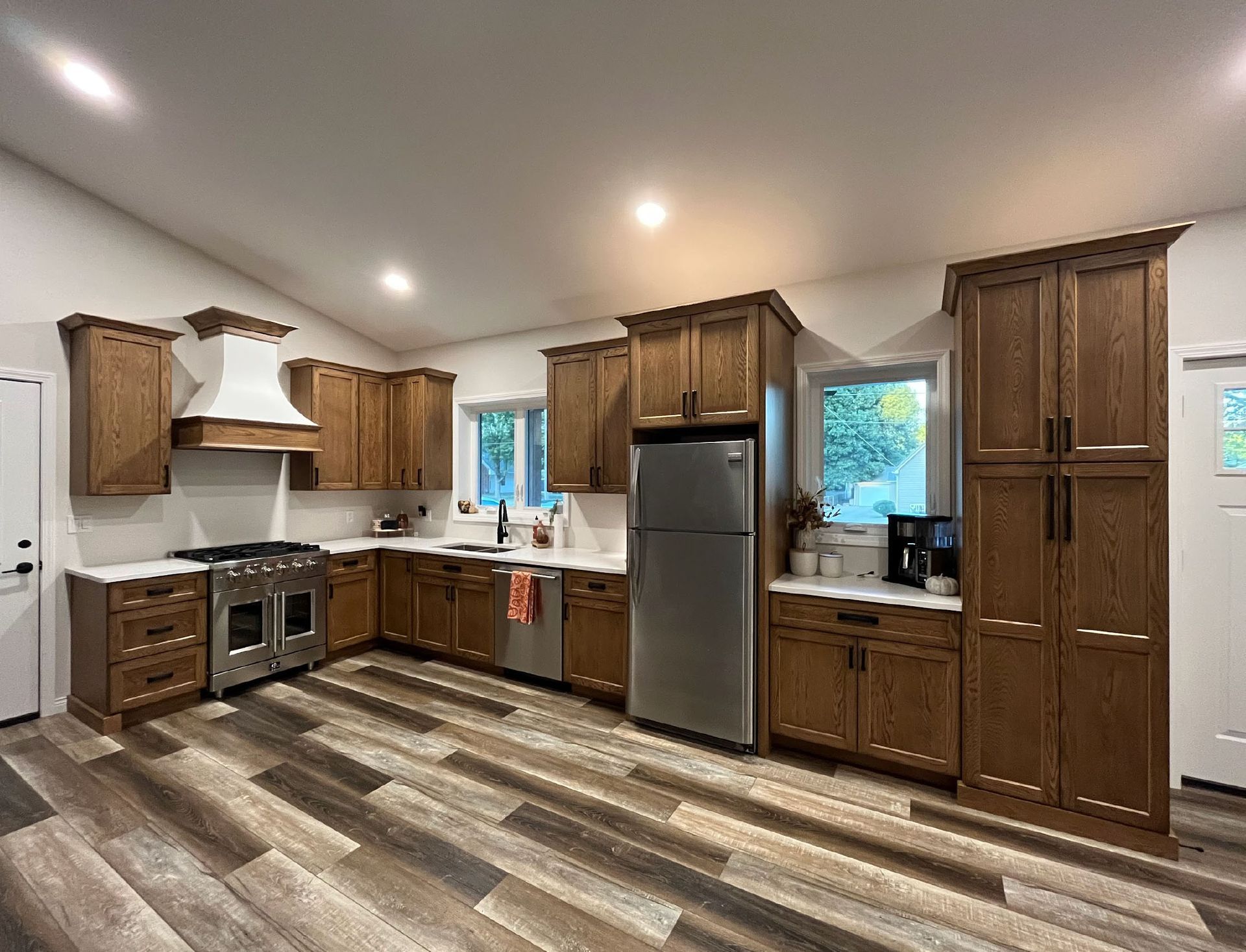 Newly renovated kitchen with wooden cabinets, stainless steel appliances, and wood-look flooring.