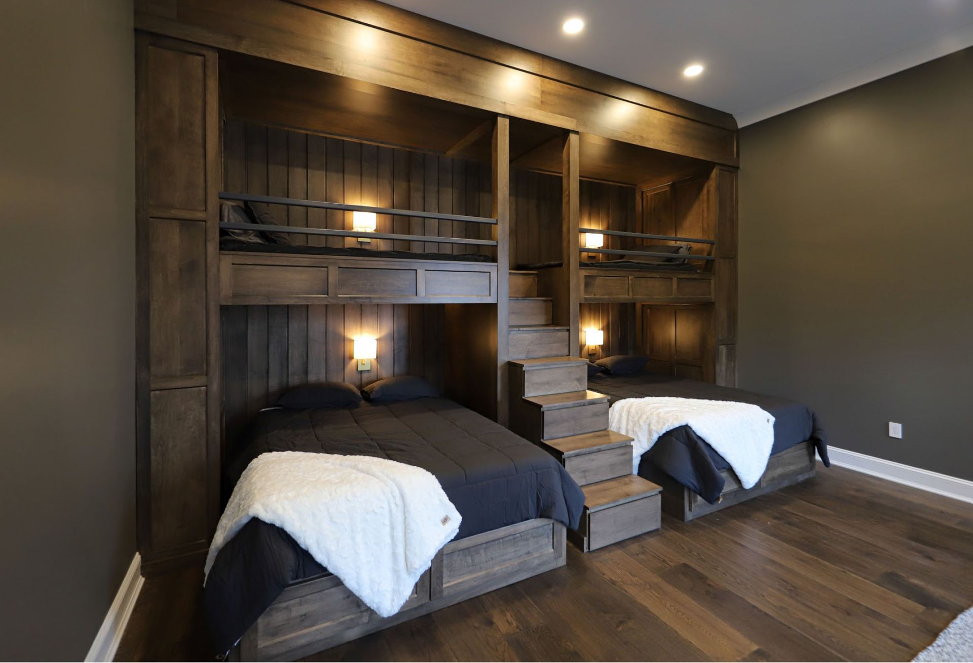 Dark wood bunk beds in a room with hardwood floors and dark gray walls.
