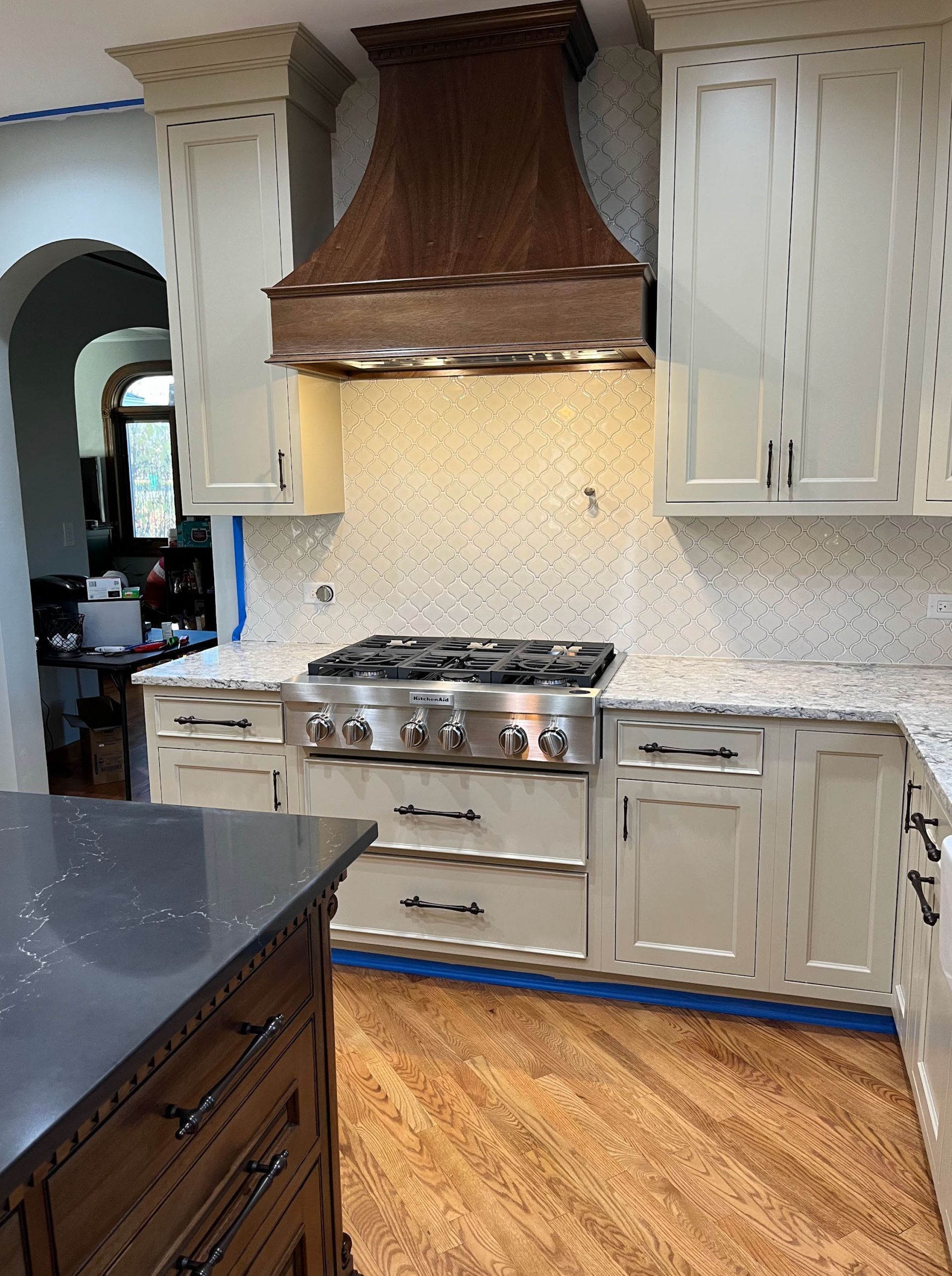 Kitchen with light cabinets, stainless steel range, copper hood, and speckled backsplash.