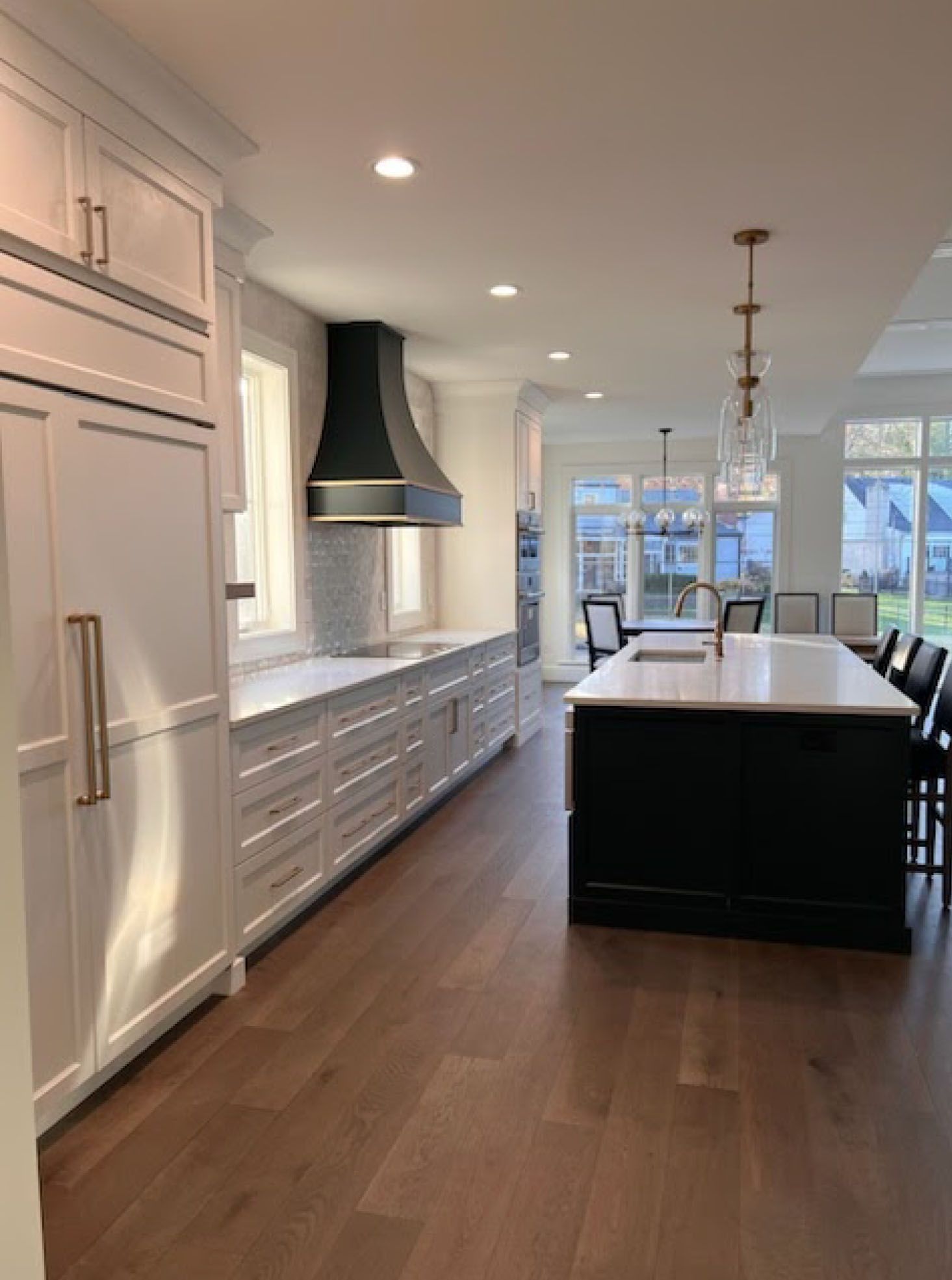 Modern kitchen with white cabinets, dark island, and black range hood.