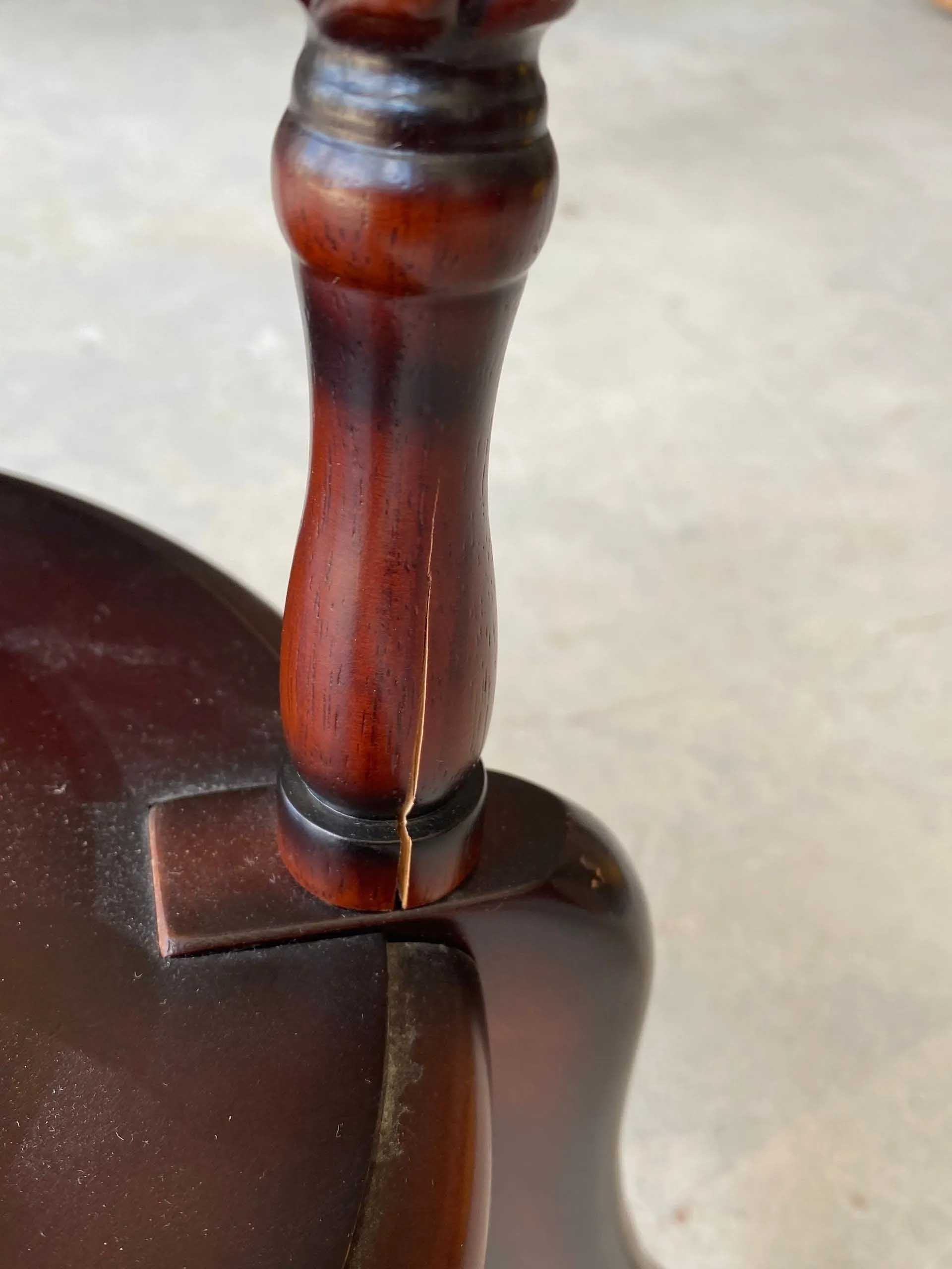 Close-up of a dark brown wooden table leg with a long crack running vertically.