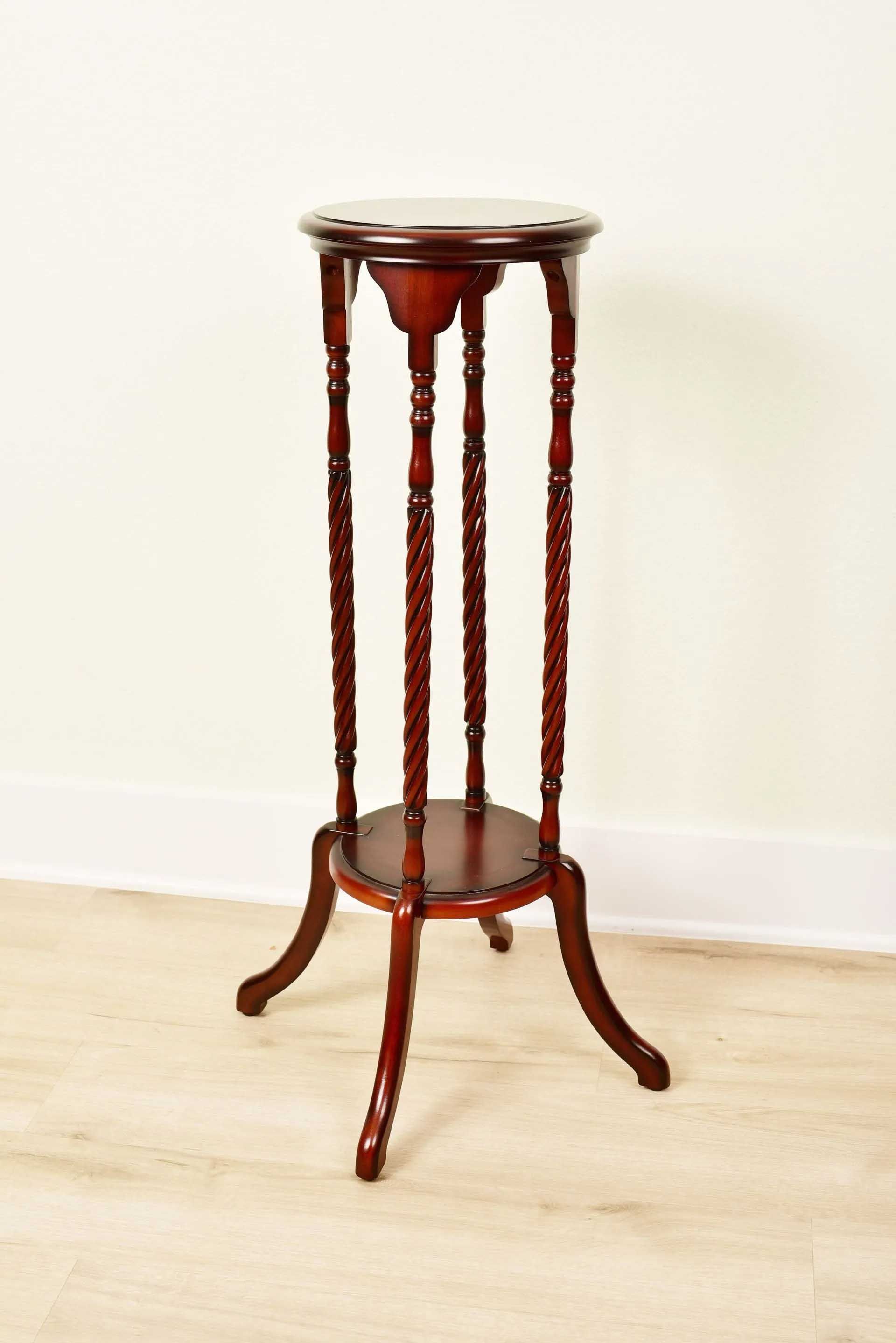 Dark wood plant stand with a round top and three decorative support posts.
