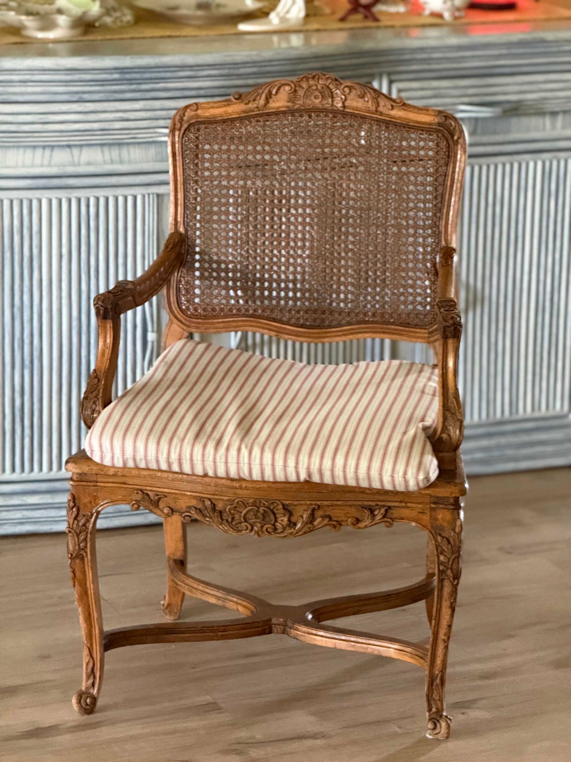 Wooden armchair with cane back and striped cushion.