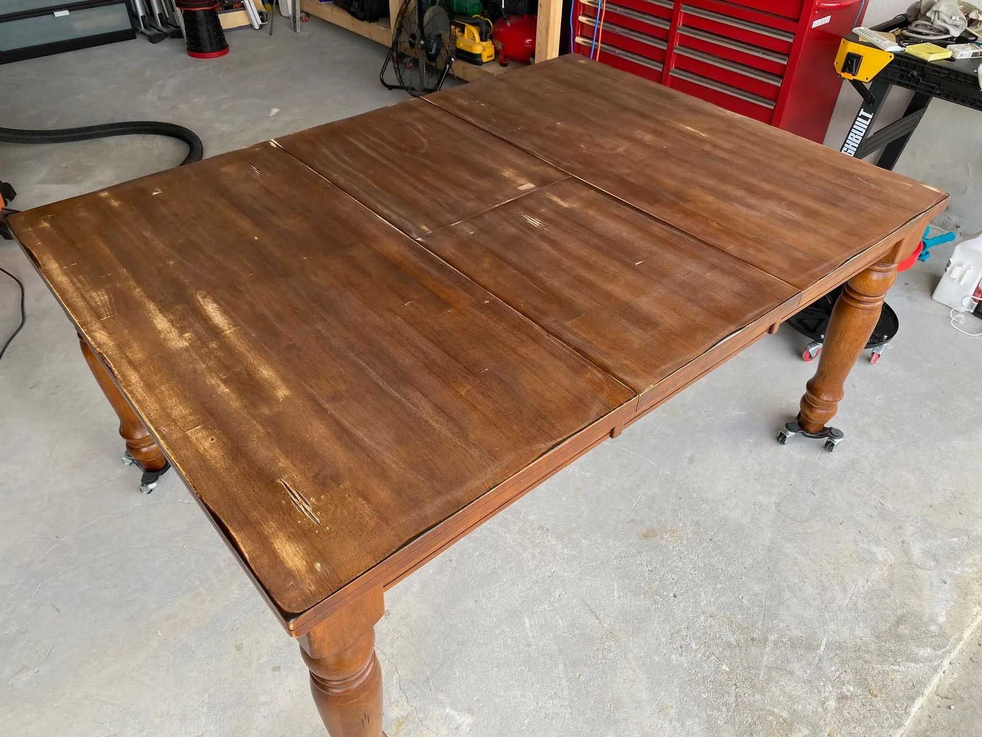 Brown wooden table with wear and tear, set in a garage.