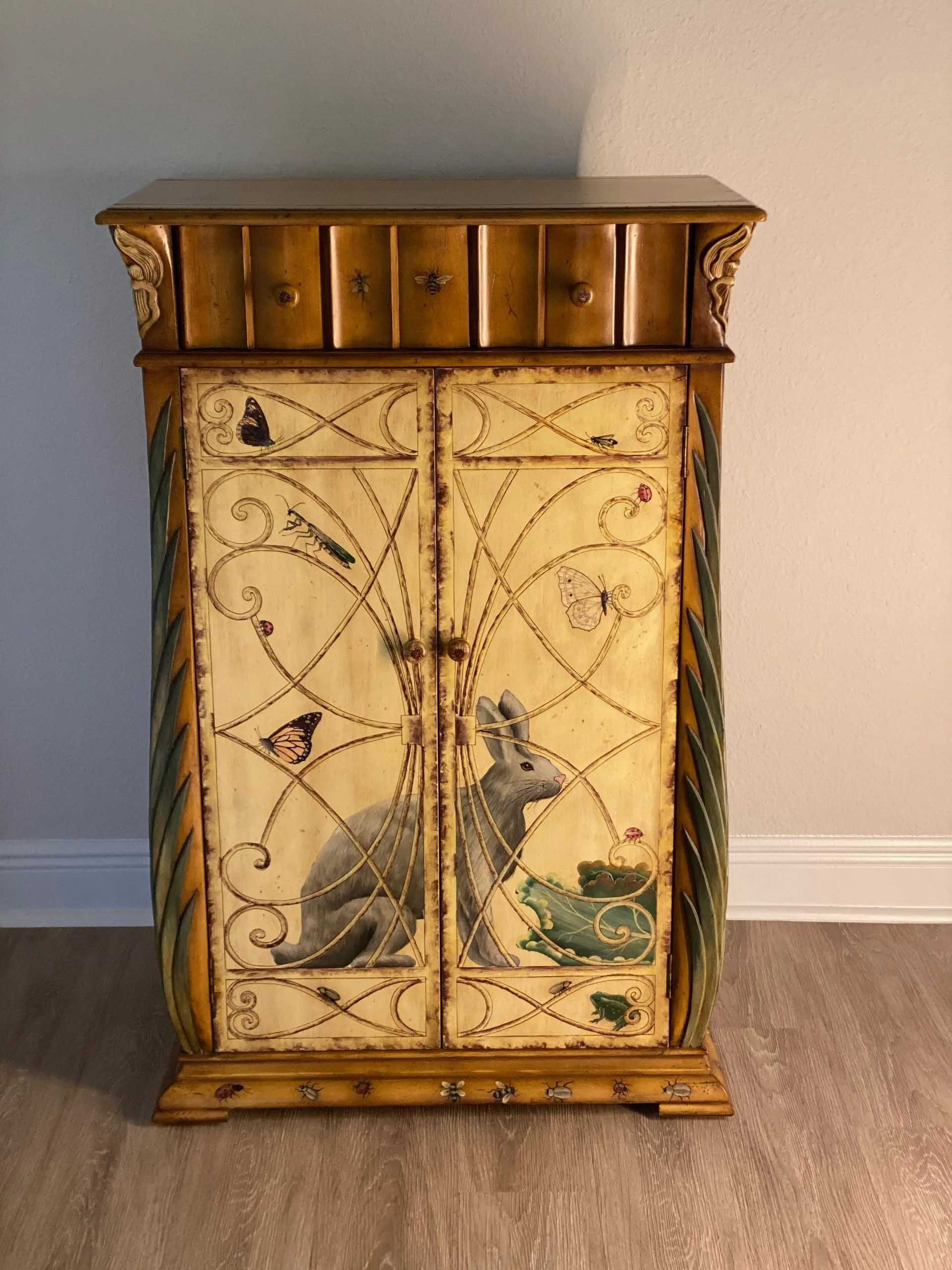 Cabinet with painted rabbit and frog, adorned with butterflies and vines; light brown with gold accents.