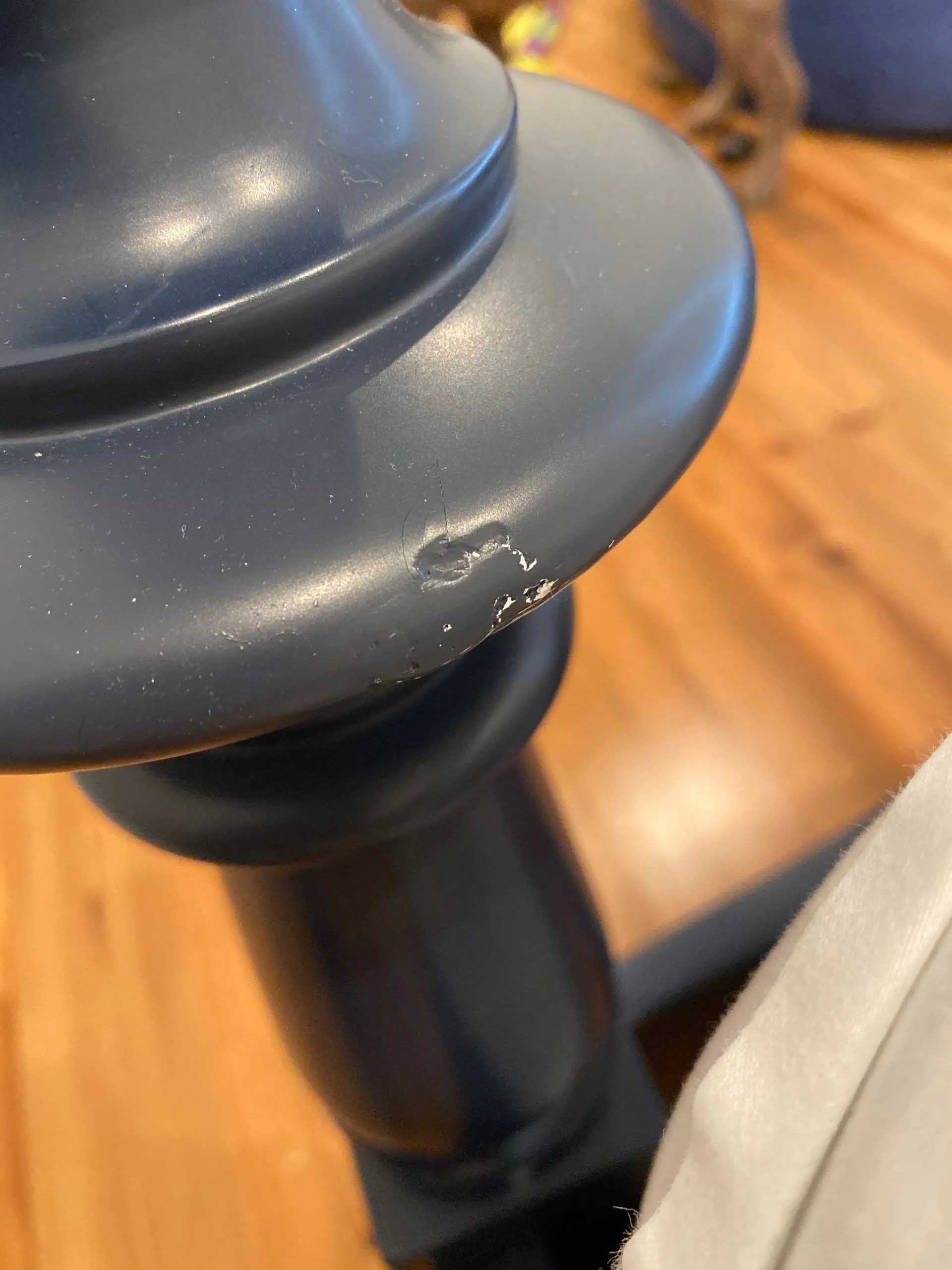 Close-up of a blue lamp base with a chipped edge.
