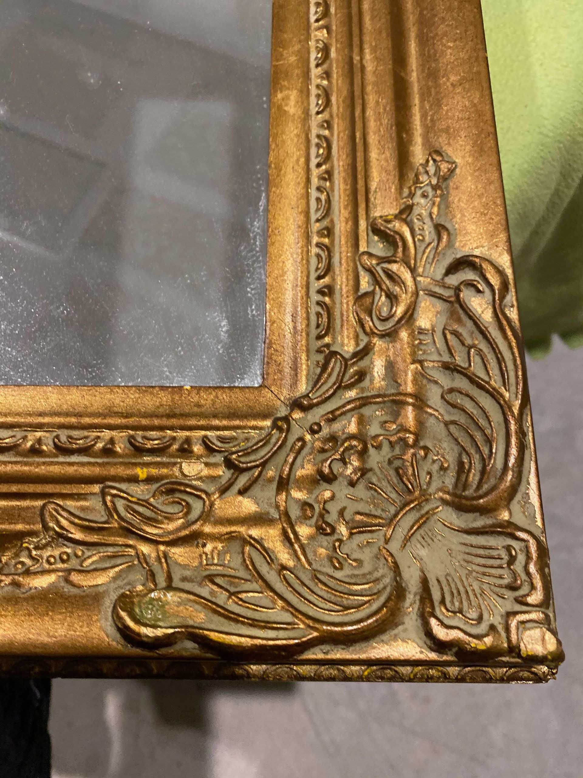 Gold ornate mirror frame corner detail.