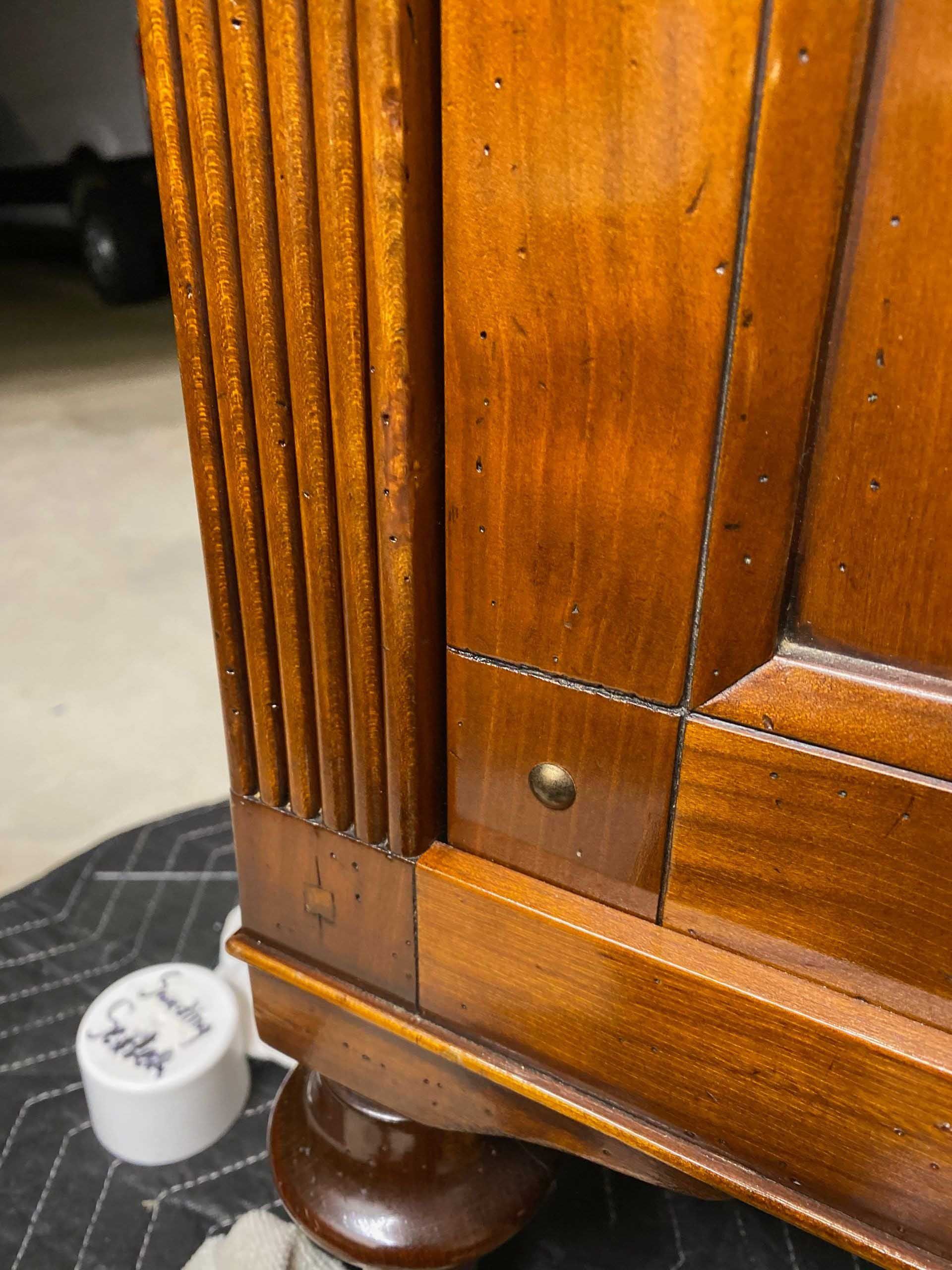 Wooden cabinet corner with fluted detail and brass rivet.
