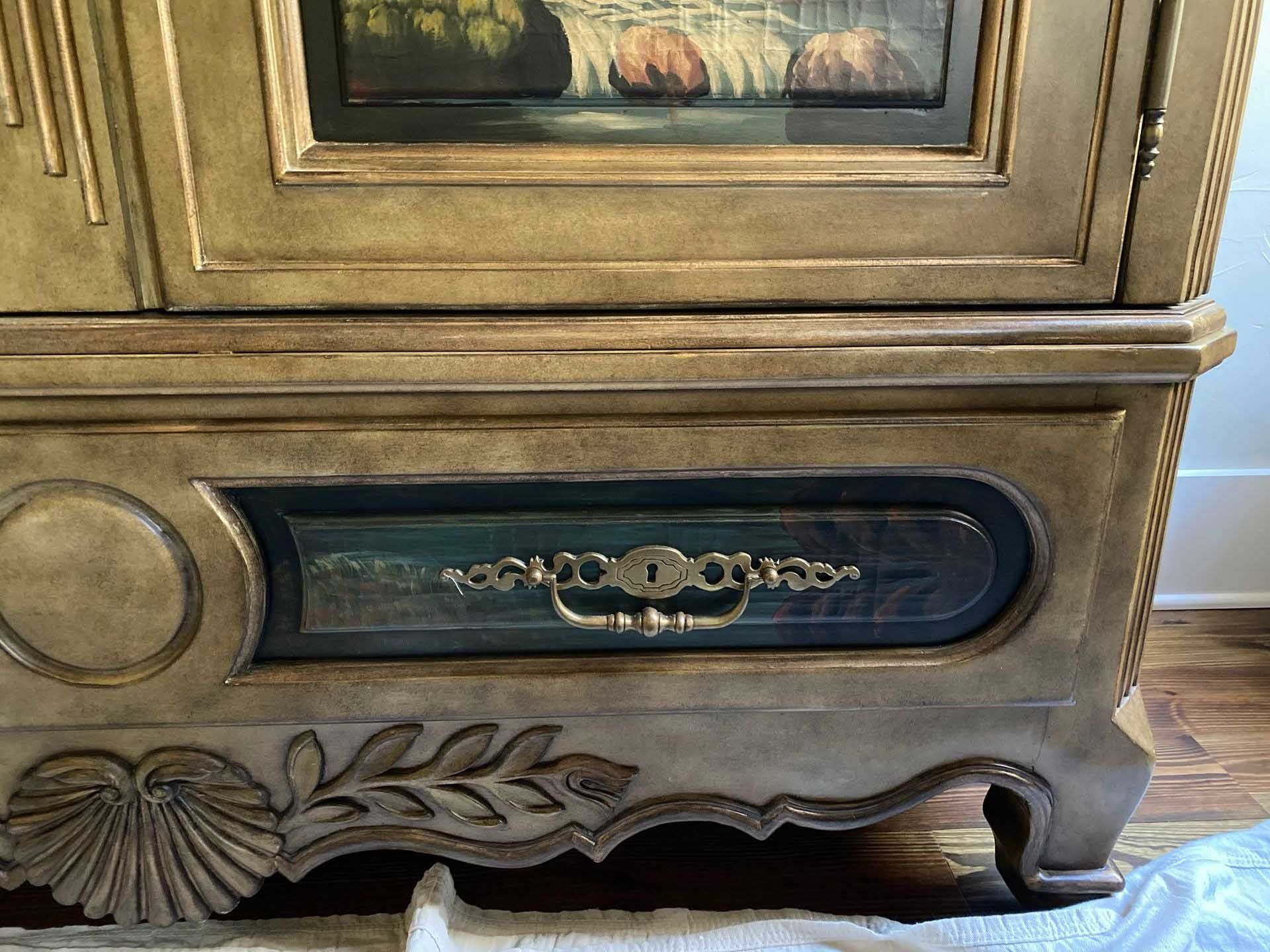 Antique cabinet with a painted top panel, drawer with brass handle, and ornate details.