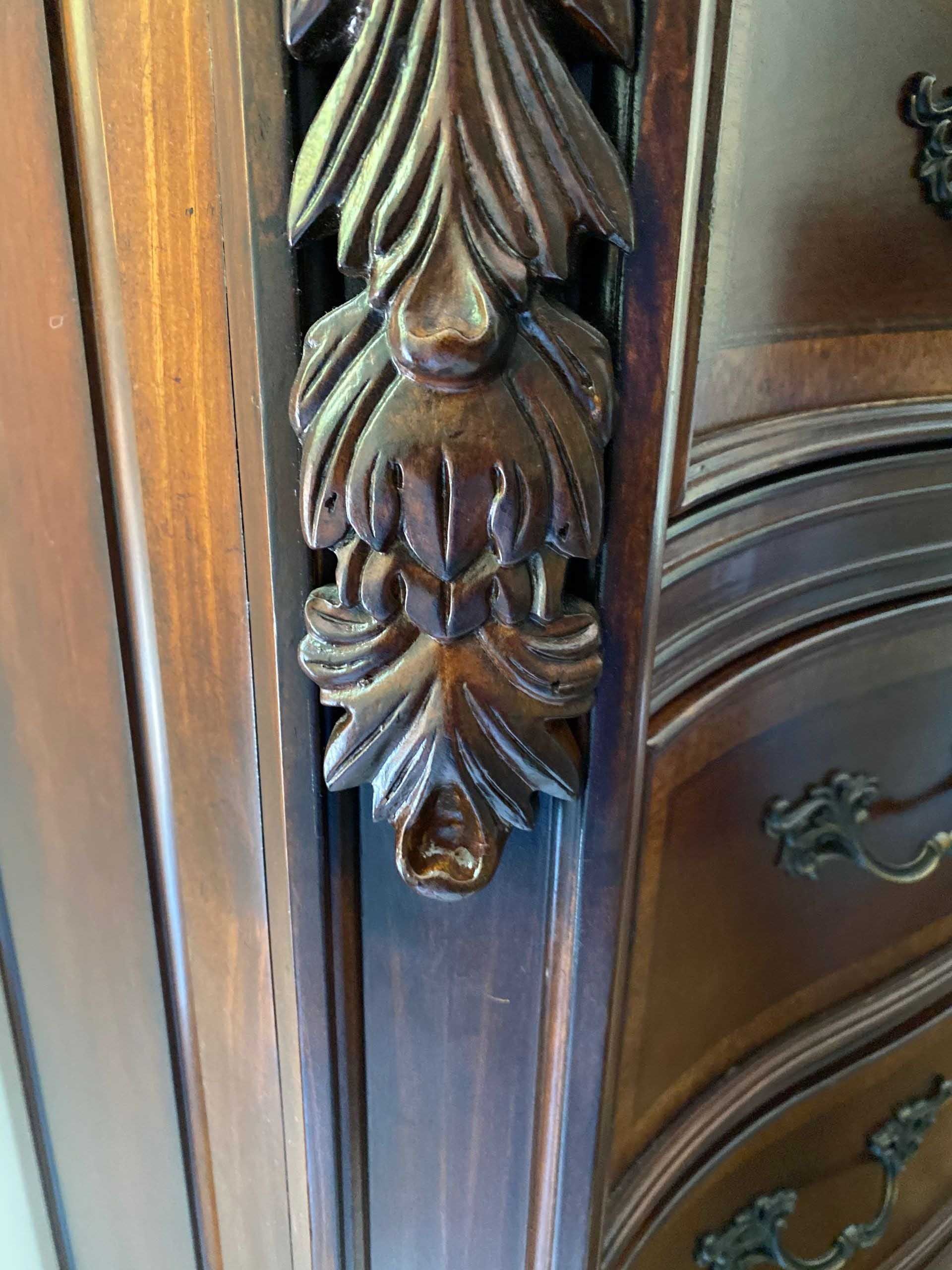 Close-up of a carved wooden decorative element on furniture, featuring leaf-like designs.