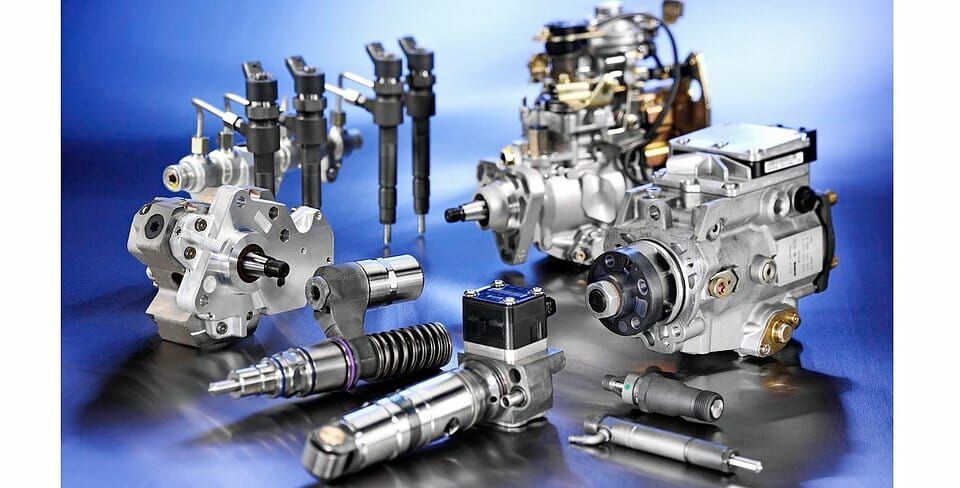 Various fuel injection system components, including pumps and nozzles, arranged on a reflective surface.