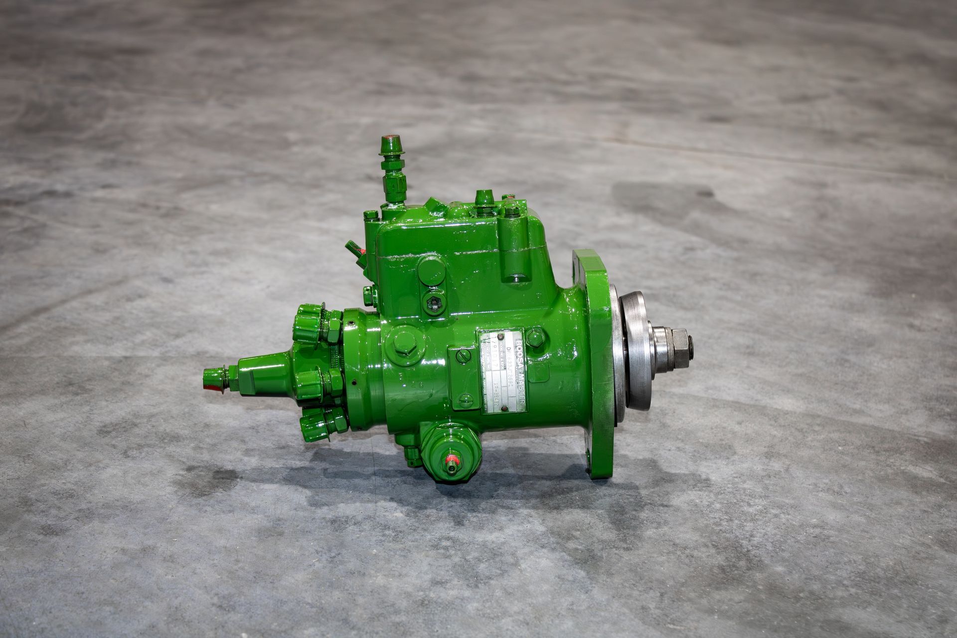 Green industrial pump or motor assembly on a gray concrete floor