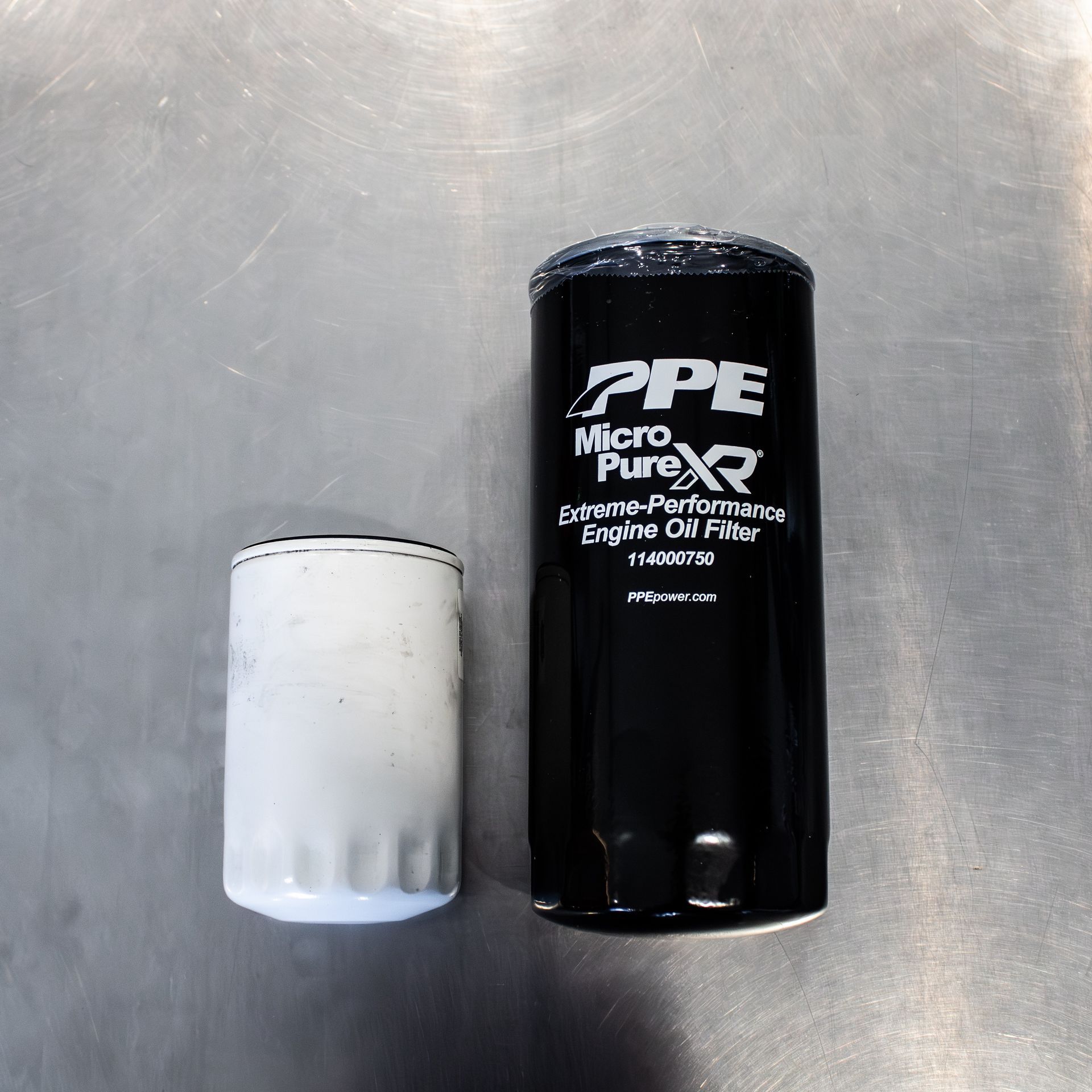 Two cylindrical filters on a metal surface, one white and one black, labeled PPE MicroPure.