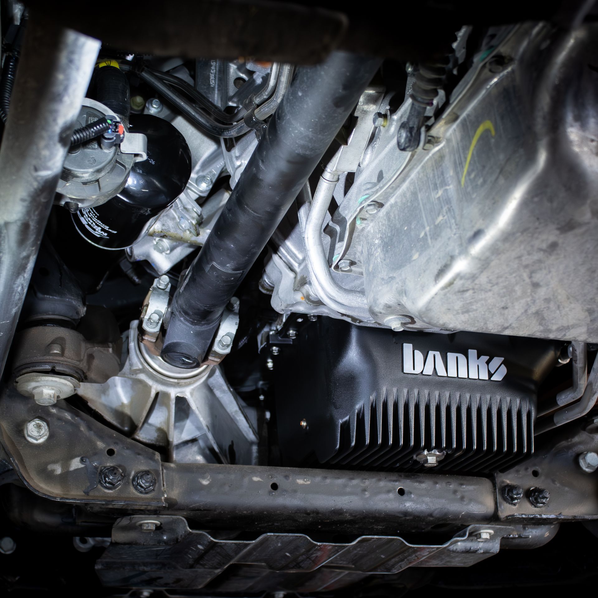 Undercarriage view of a vehicle with exposed mechanical parts, a black Banks air filter, and metal framing.