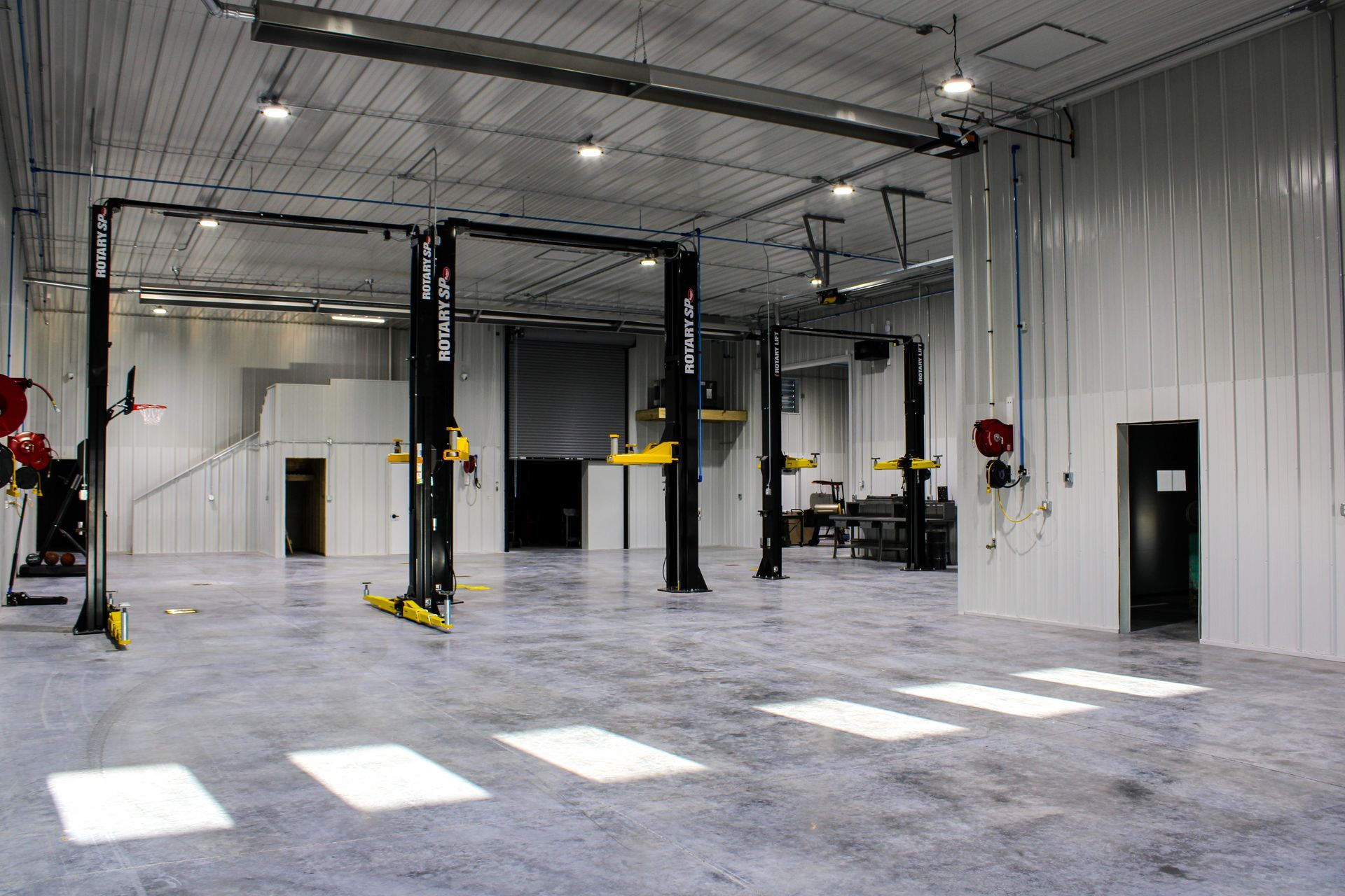 Empty auto repair shop interior with car lifts and bright overhead lights
