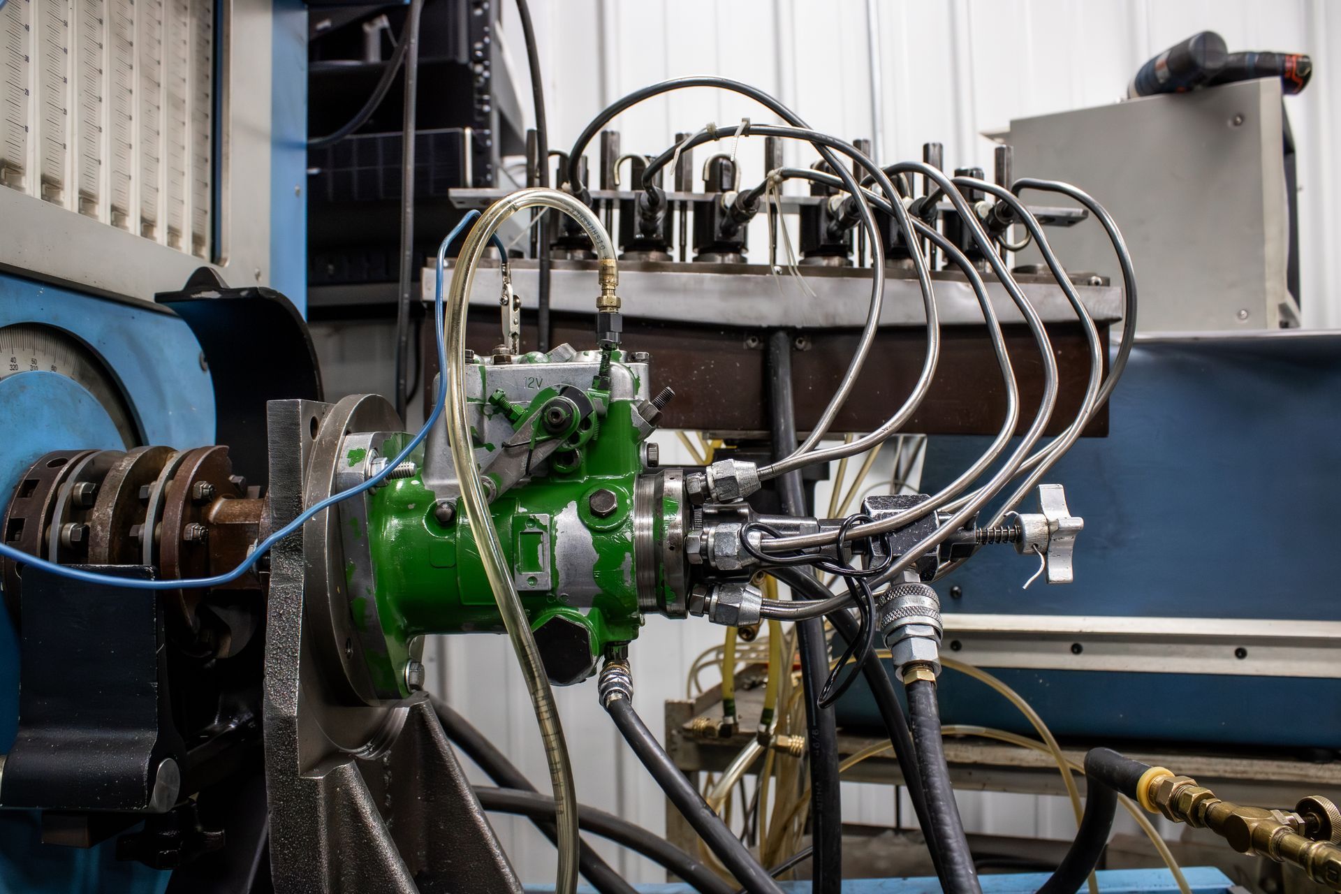 Industrial machinery with green hydraulic components, black hoses, and metal piping in a workshop setting