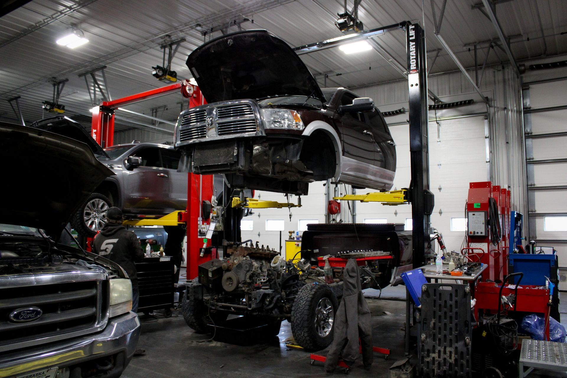 A car body hoisted on a lift in a garage, exposing the engine and chassis for repairs.