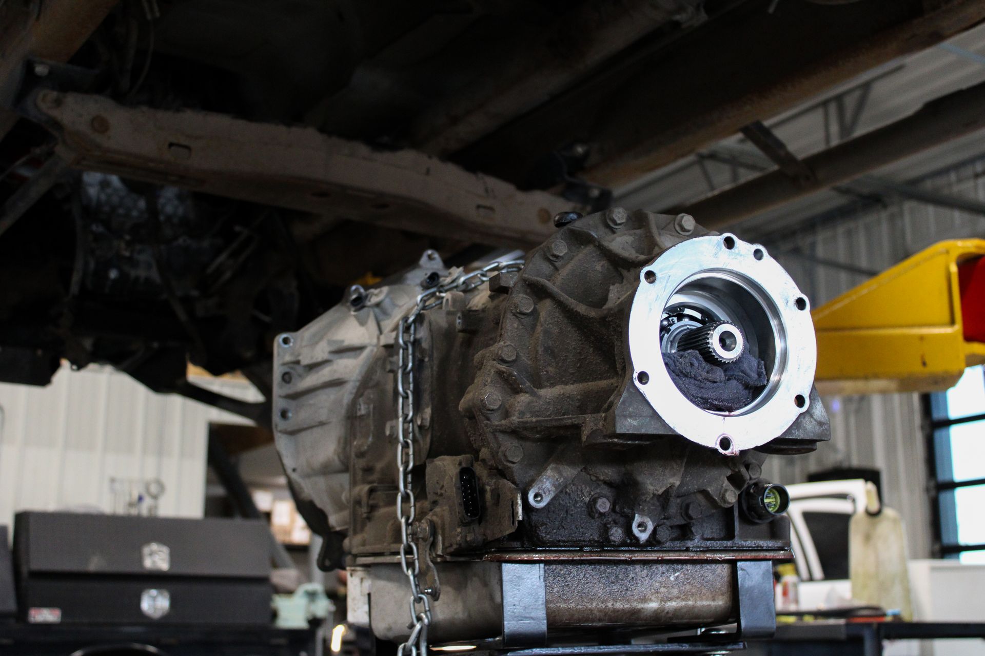An automotive transmission removed from a vehicle and positioned on a lift in a workshop.