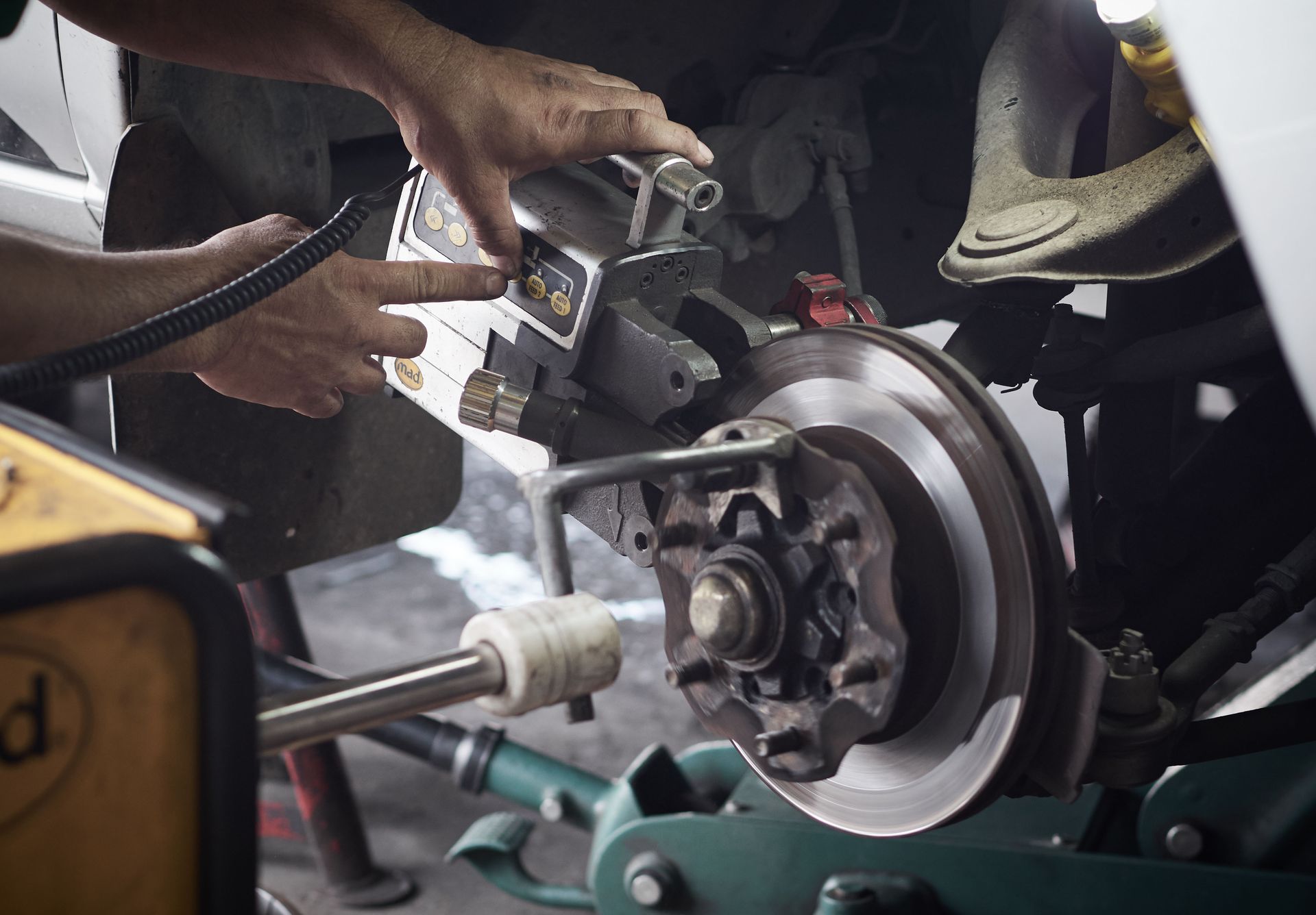 A mechanic uses a disc brake lathe to resurface a vehicle's brake rotor in an auto repair shop.