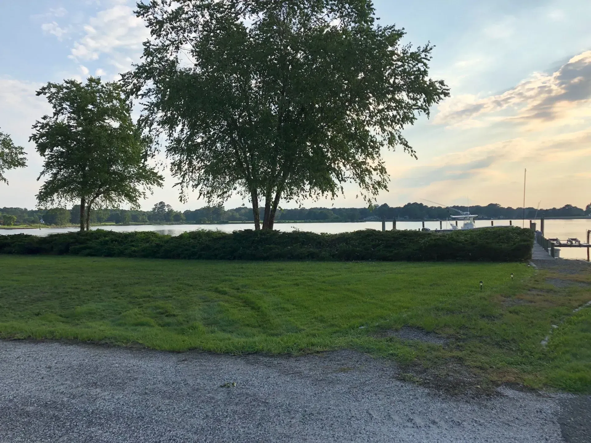 Lush green lawn with trees and a lake in the background; a serene outdoor setting.