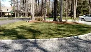Roundabout with grass, trees, and a car in a residential area.