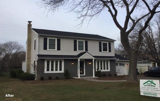 Two-story house with gray siding, black shutters, and a dark roof.