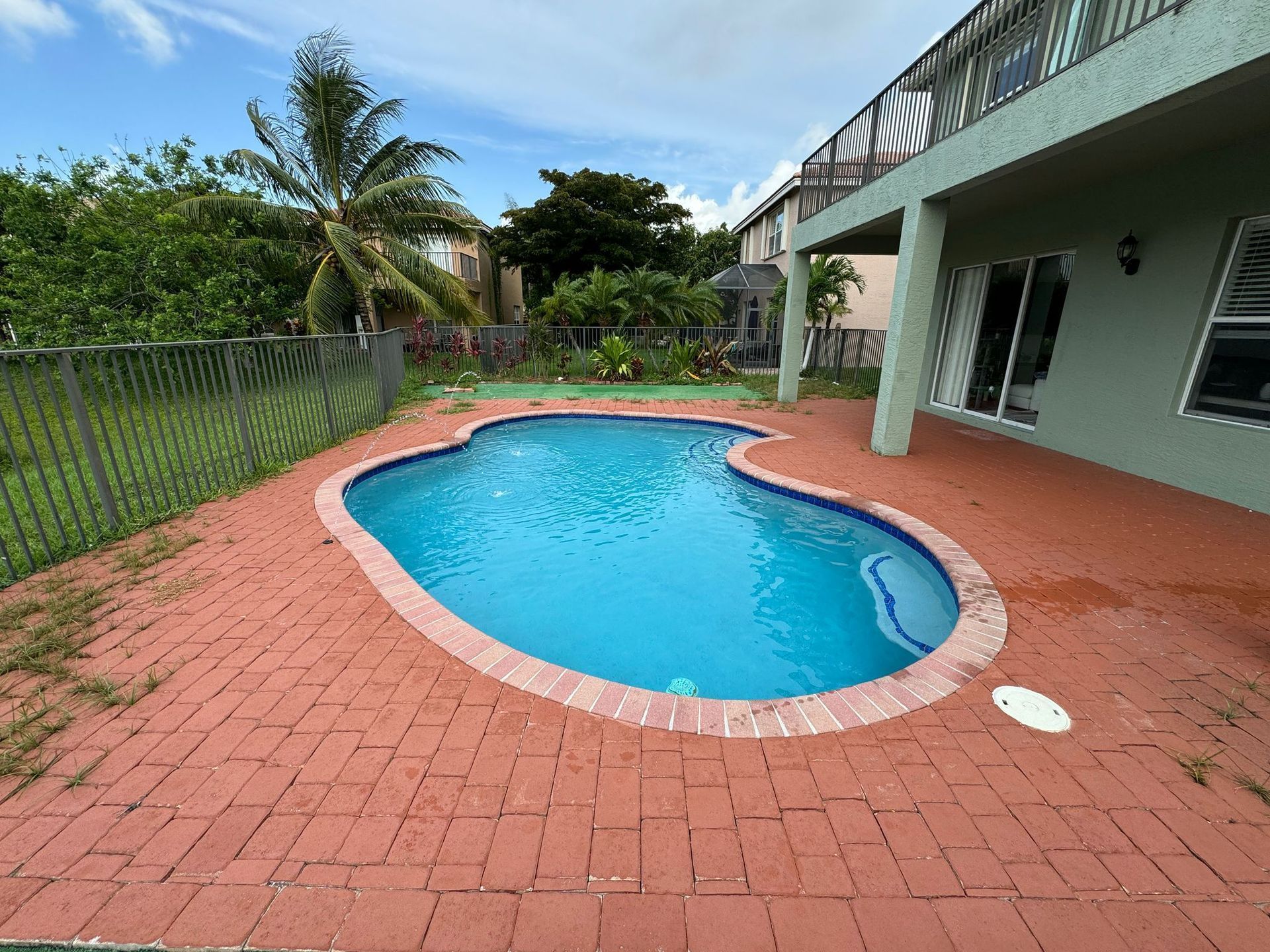 A large swimming pool is in the backyard of a house.