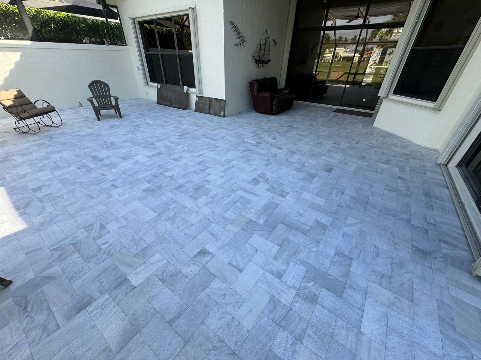 A patio with a gray tile floor and chairs.